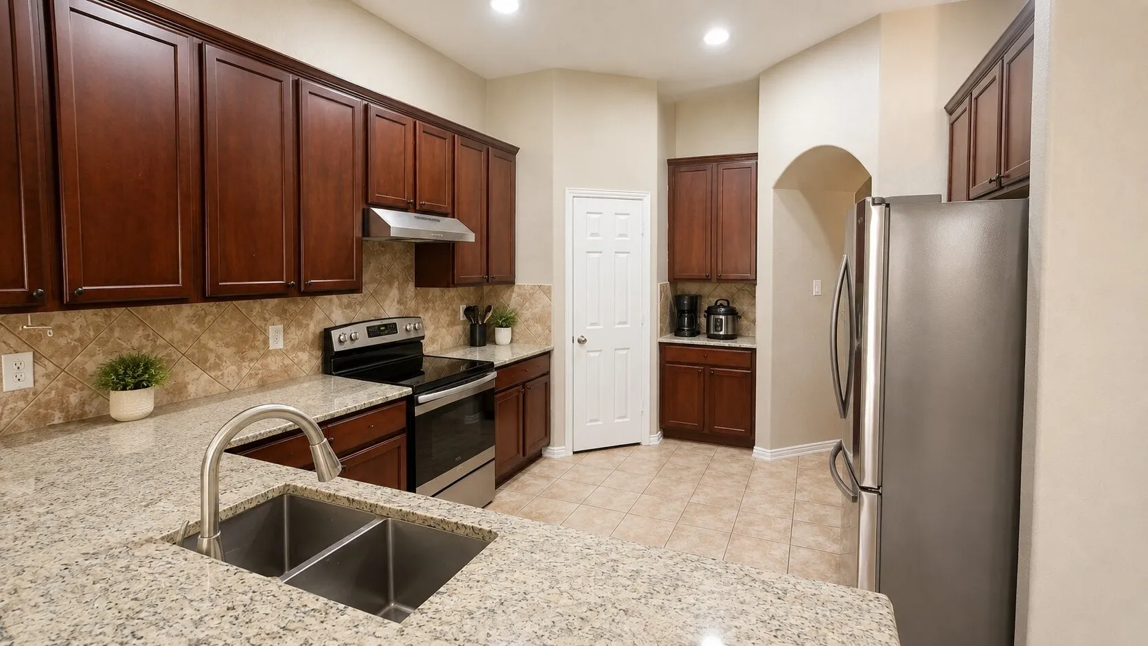 Kitchen featuring granite countertops, wood cabinetry, stainless steel appliances, a tile backsplash, and recessed lighting