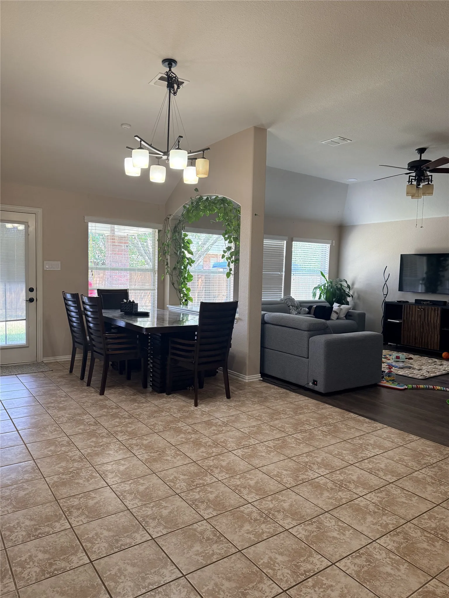 Tile flooring, arched entryway, wood-finish flooring, ceiling fan, and chandelier lighting