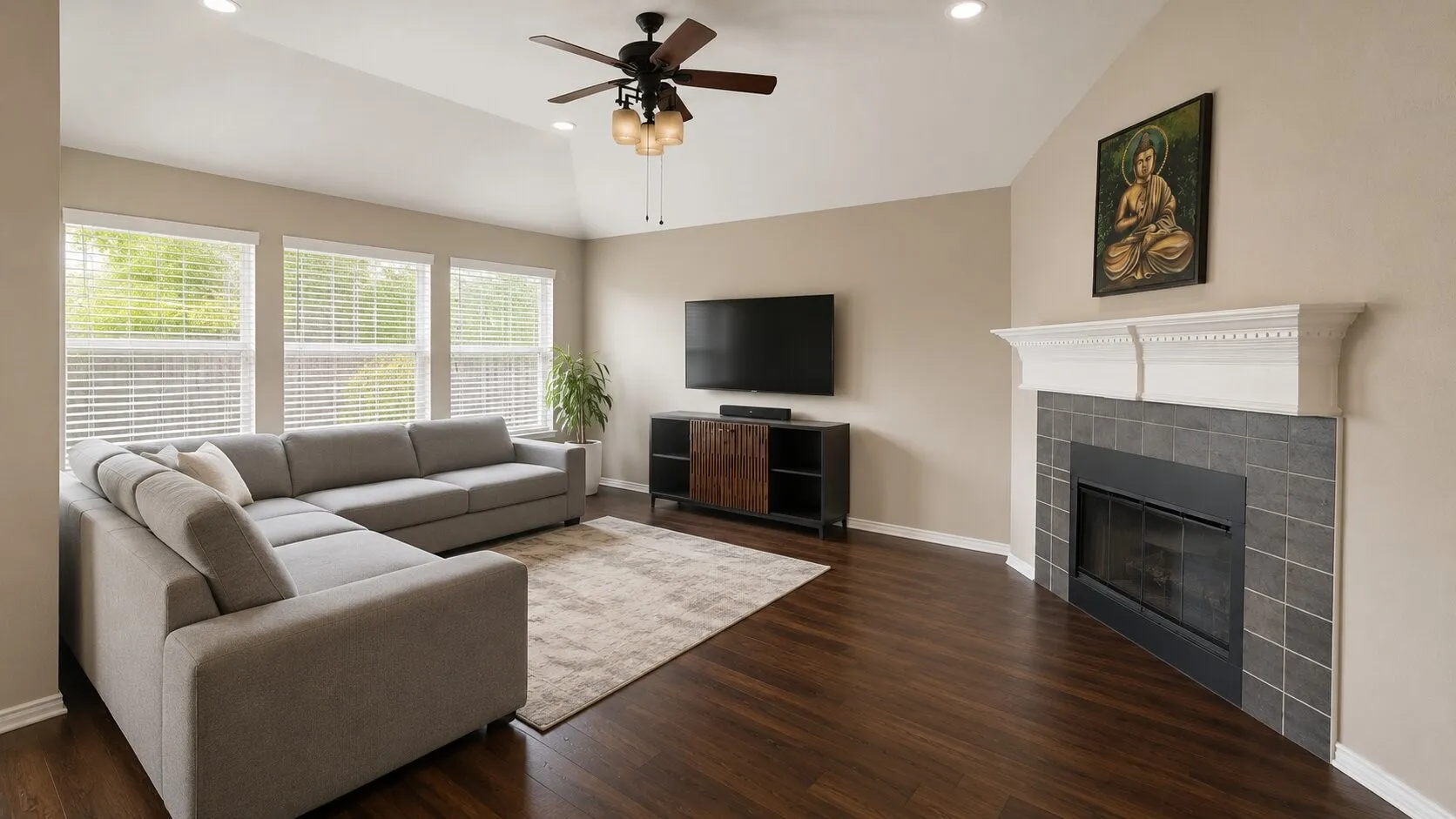 Vaulted ceilings with recessed lighting, wood-finish flooring, a fireplace with a white mantel and tile surround, and multiple windows with blinds