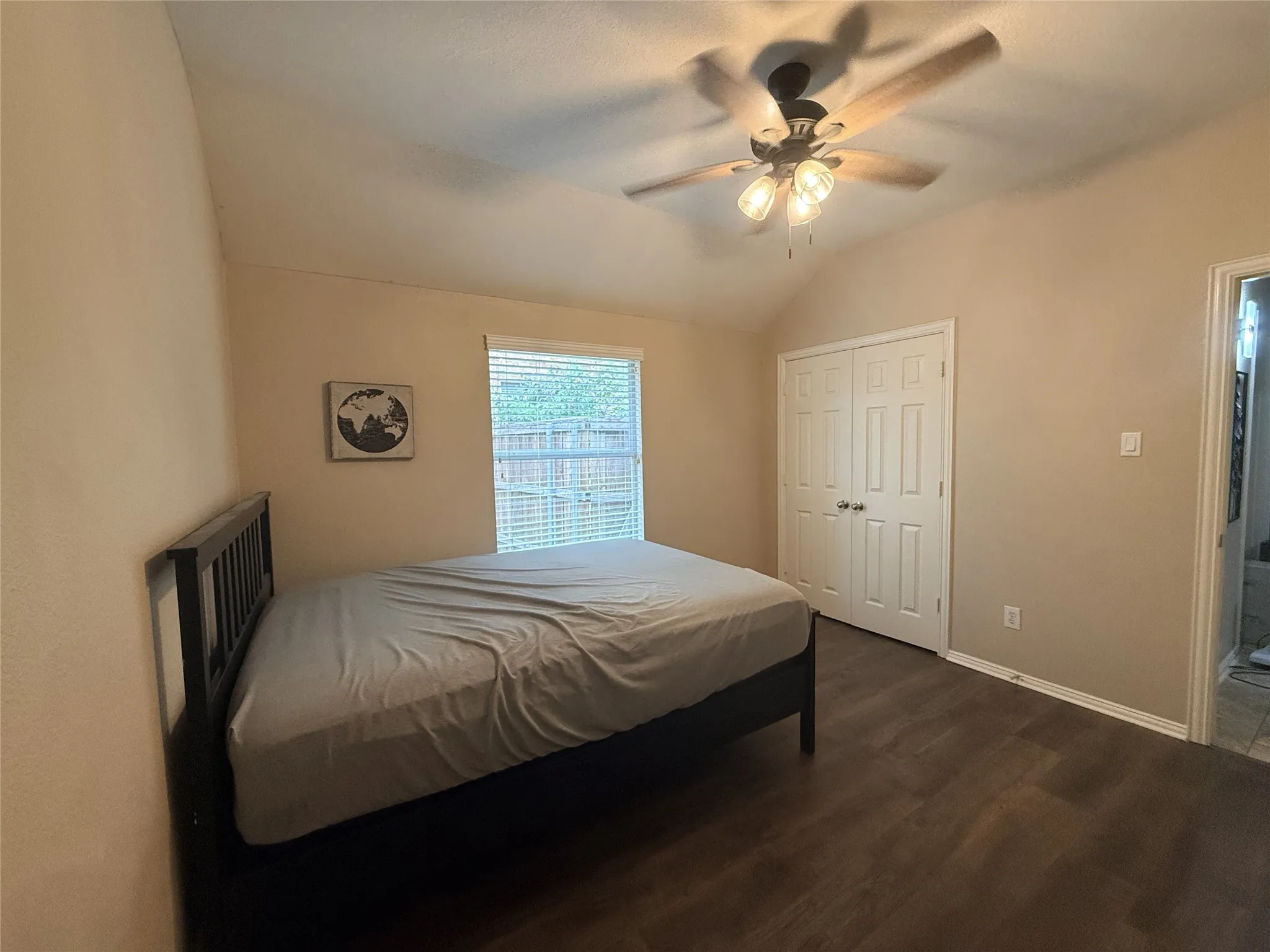Vaulted ceiling, wood-finish flooring, ceiling fan with light fixture, double-door closet, and window with blinds