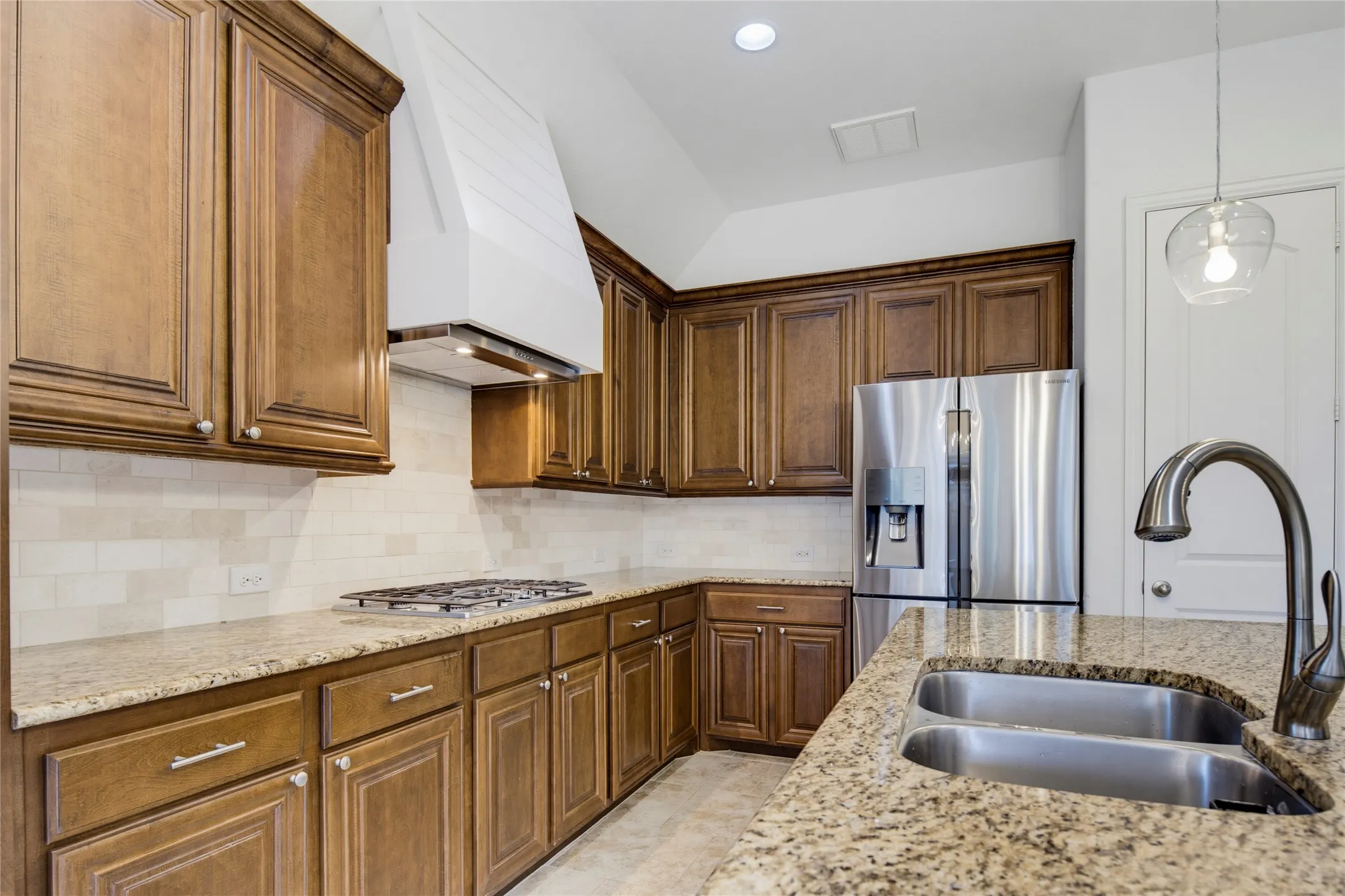 Kitchen featuring granite countertops, wood cabinetry, stainless steel appliances, a gas cooktop, and a double basin sink