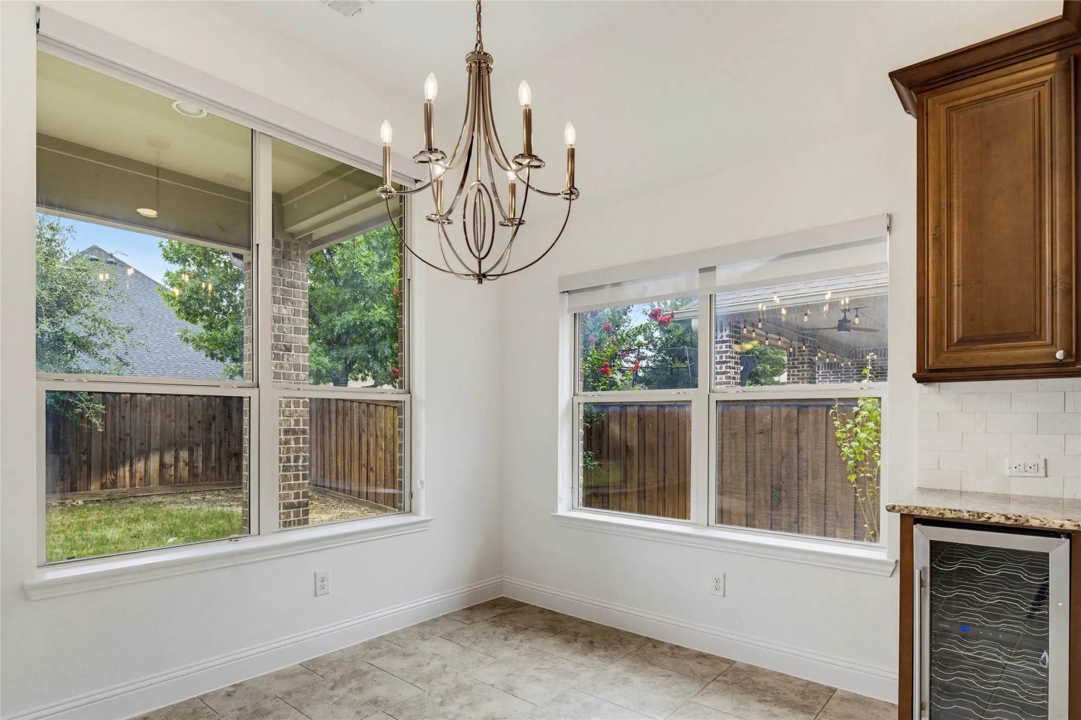 Ceiling-mounted chandelier, tiled flooring, built-in lower cabinet, built-in beverage refrigerator, and subway tile backsplash
