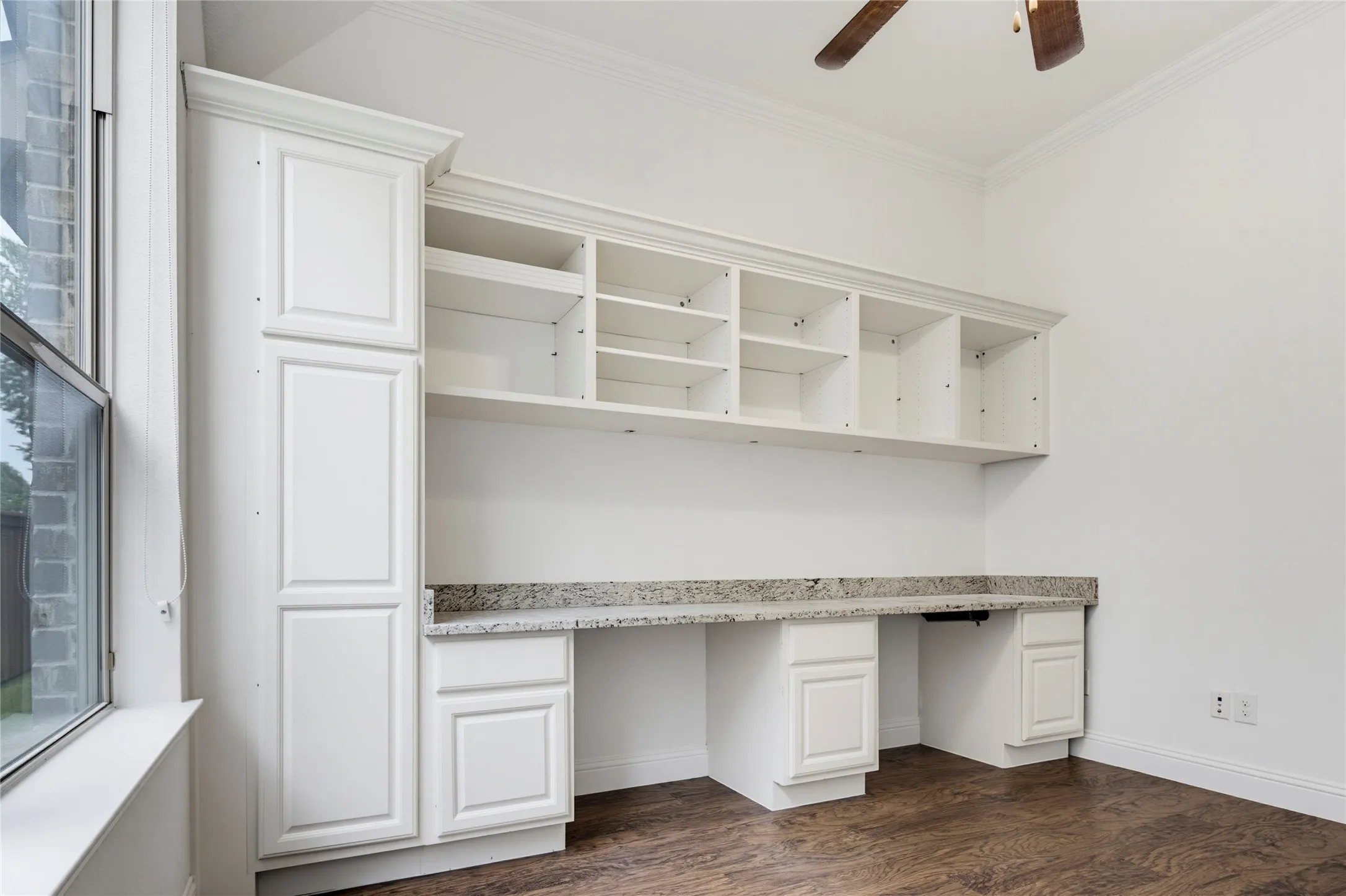 Built-in white cabinetry with open shelving, a granite-finish countertop, and wood-finish flooring