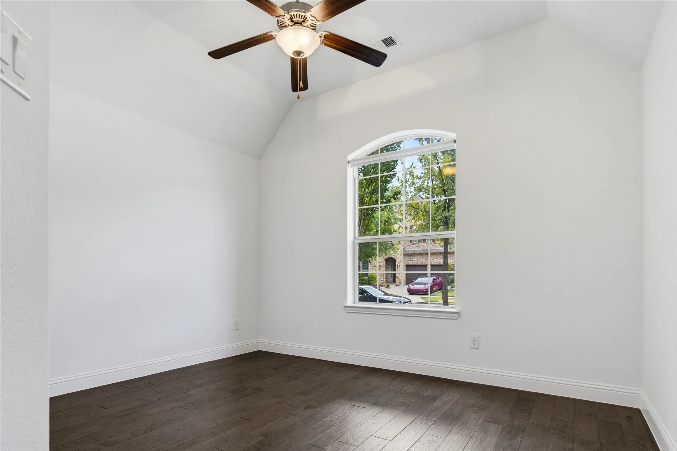 Vaulted ceiling with a ceiling fan, wood-finish flooring, and an arched window