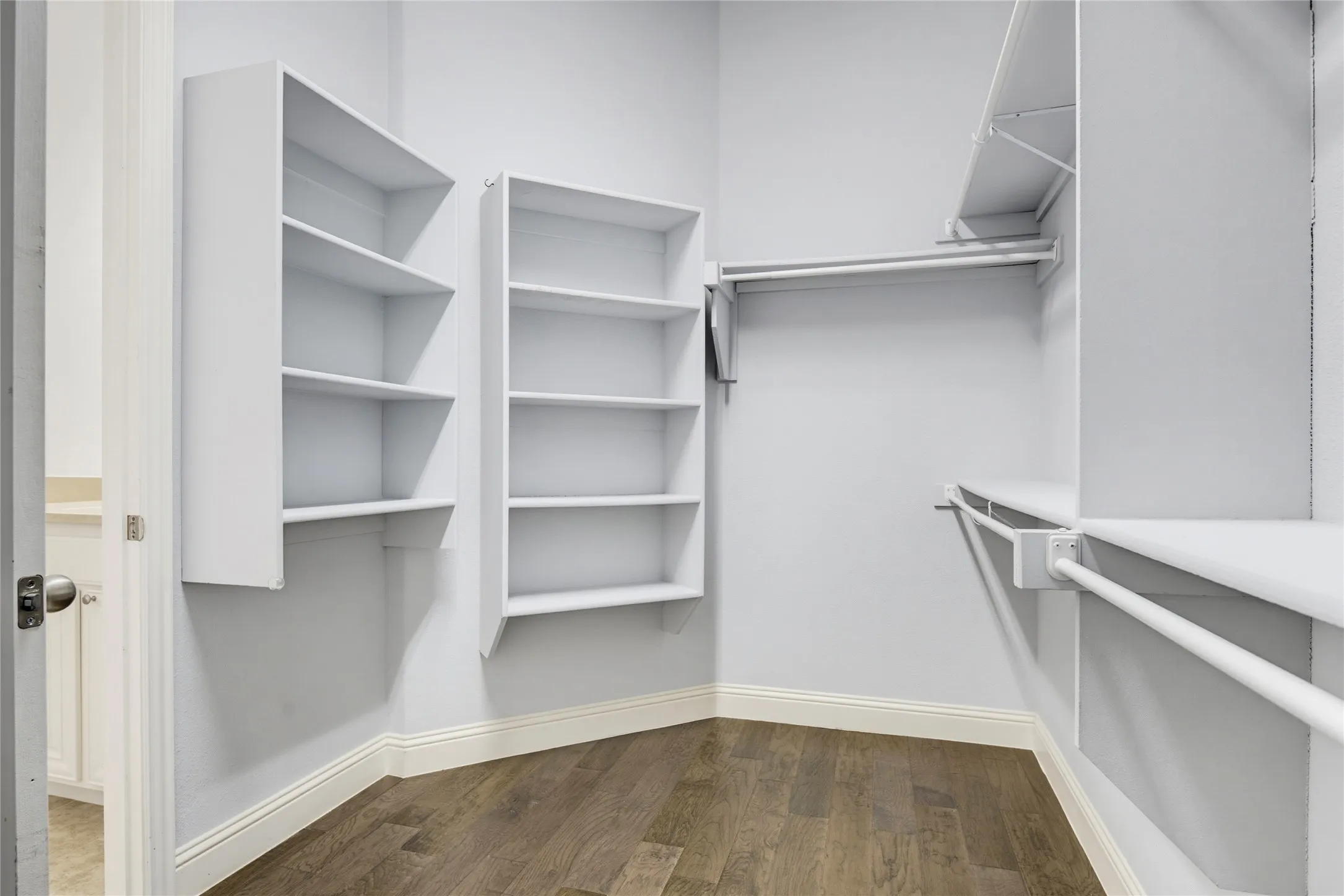 Built-in shelving, hanging rods, hard surface flooring, white walls, and white trim