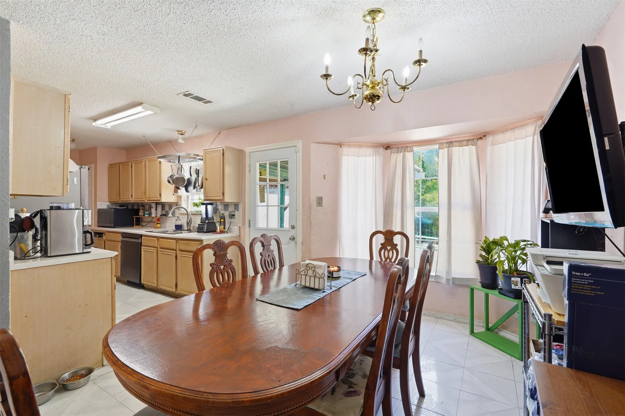Dining area with a bay window, a brass chandelier, and tile flooring
