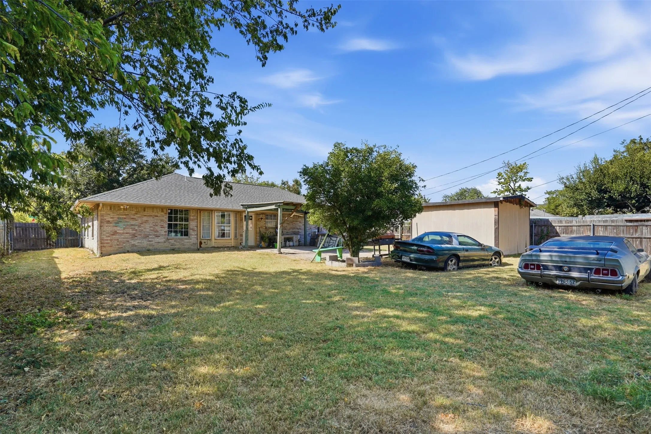 Brick exterior, covered patio, fenced yard, detached storage shed, and mature trees