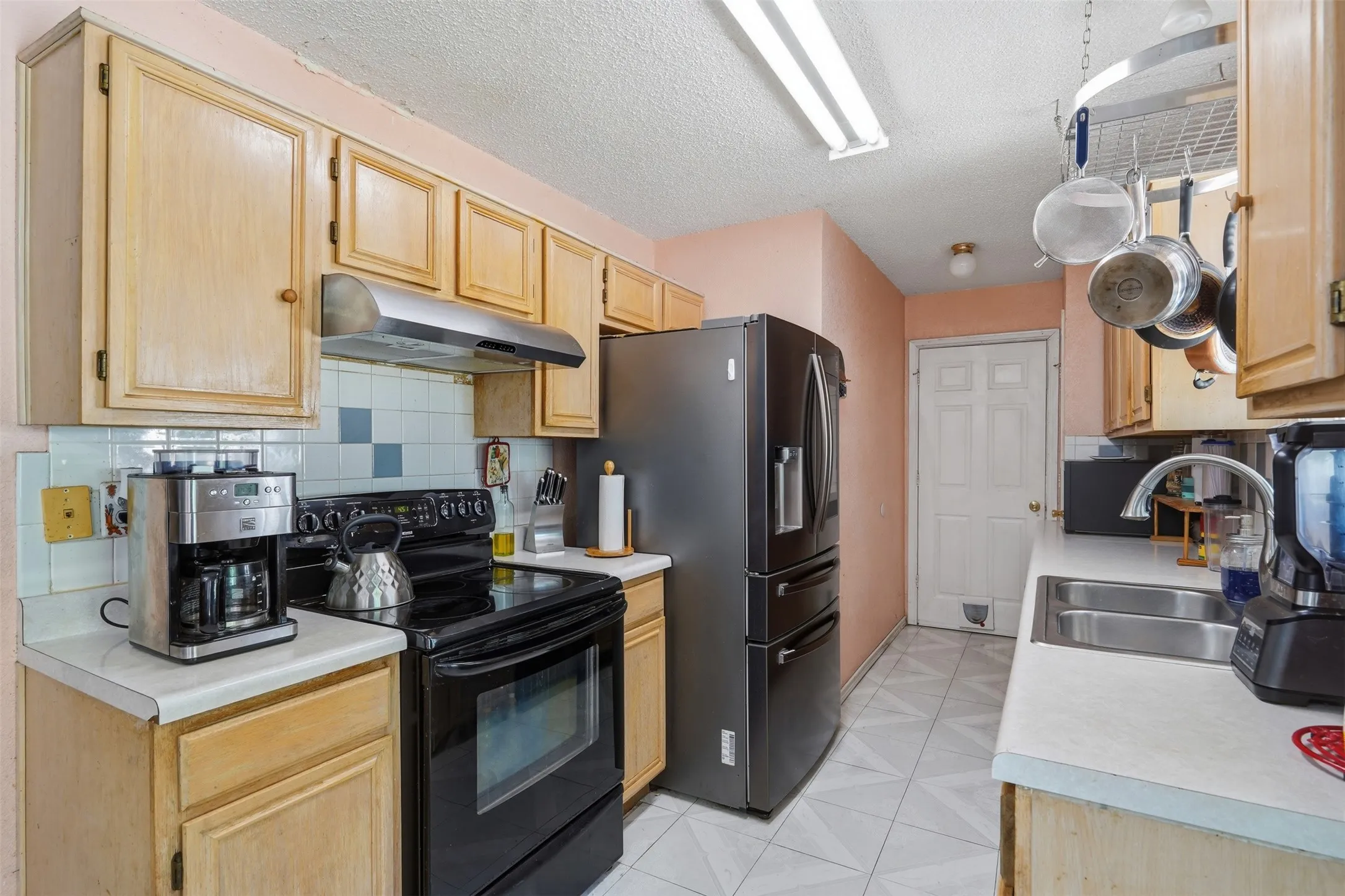 Kitchen featuring wood-finish cabinetry, a stainless steel sink with a high-arc faucet, and tiled flooring