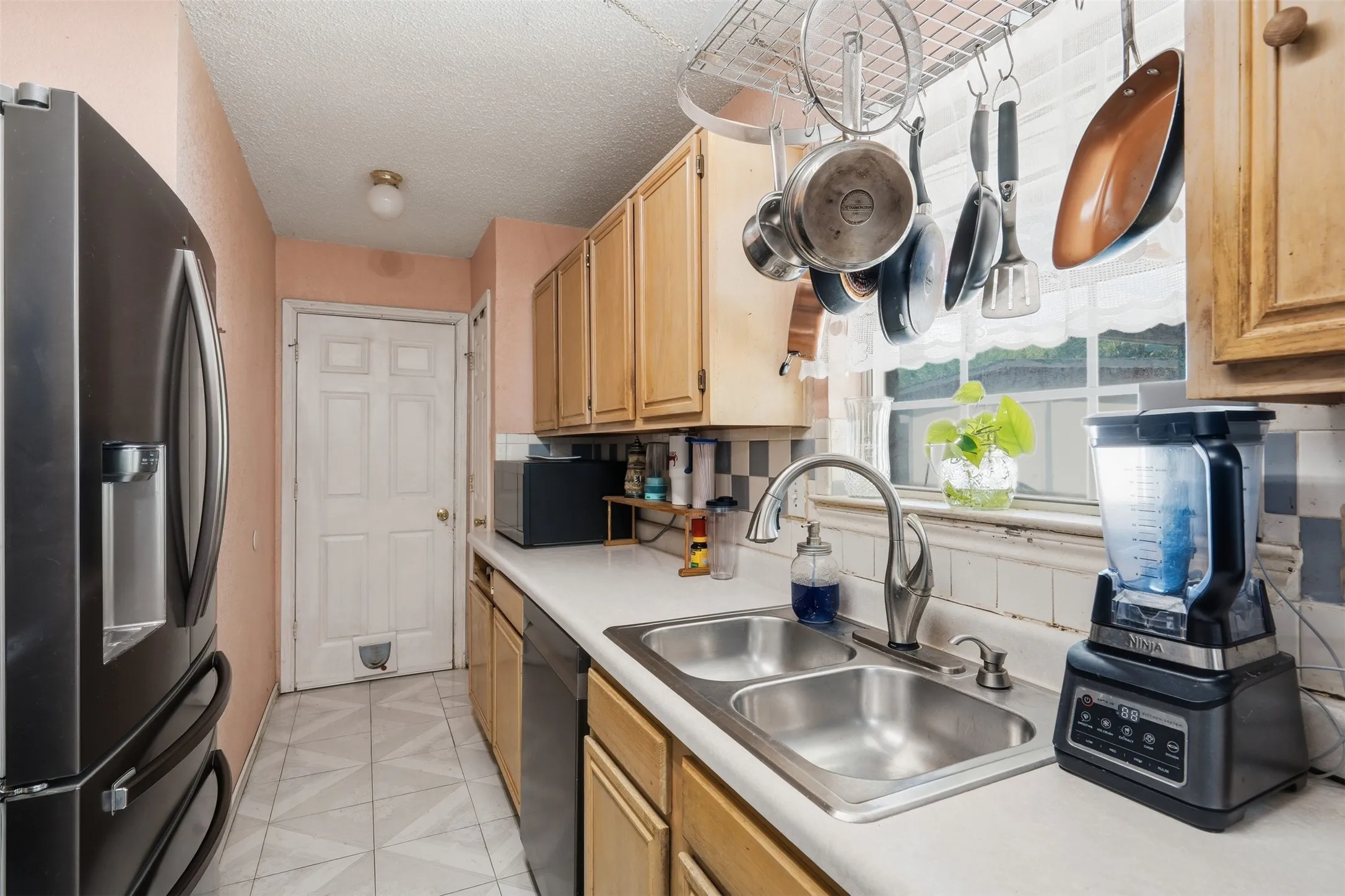 Kitchen featuring wood cabinetry, white countertops, a stainless steel double sink with a gooseneck faucet, and a stainless steel dishwasher
