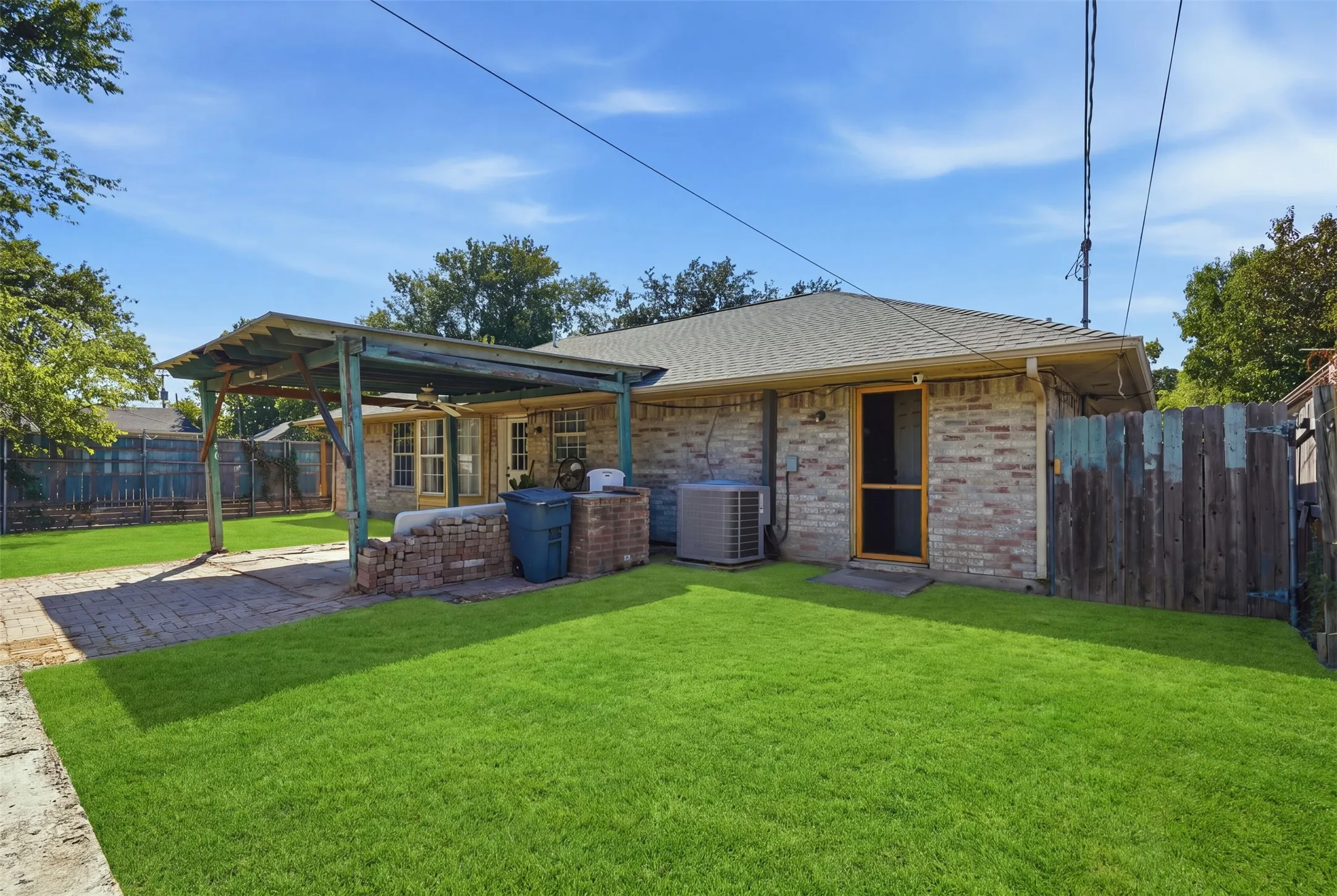 Expansive green lawn, brick exterior, covered patio structure, and brick hardscaping