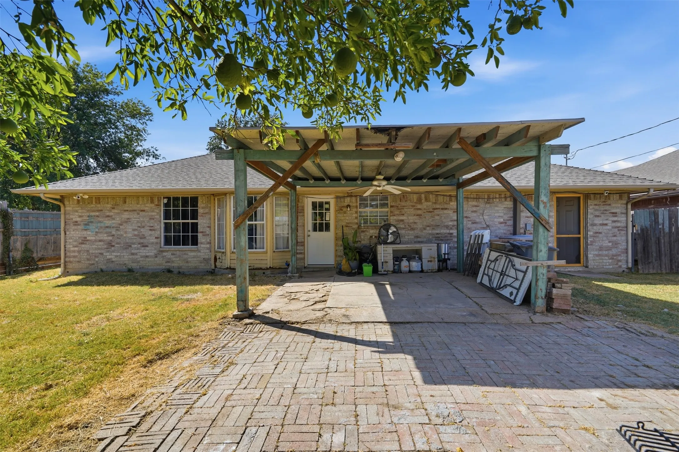 Brick exterior with multiple windows and a covered patio featuring a ceiling fan