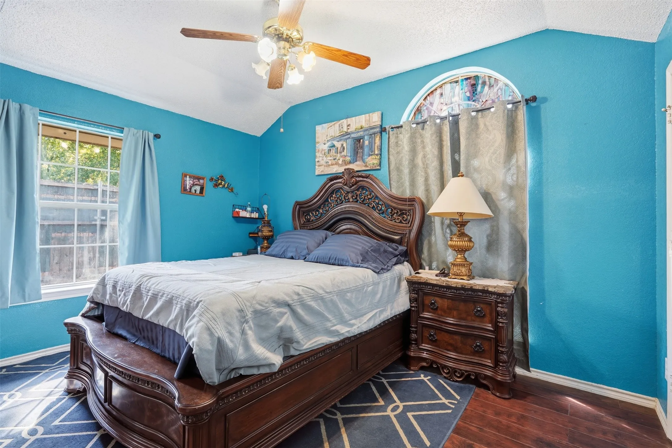Vaulted ceiling with a ceiling fan, recessed window, arched window, and wood-finish flooring