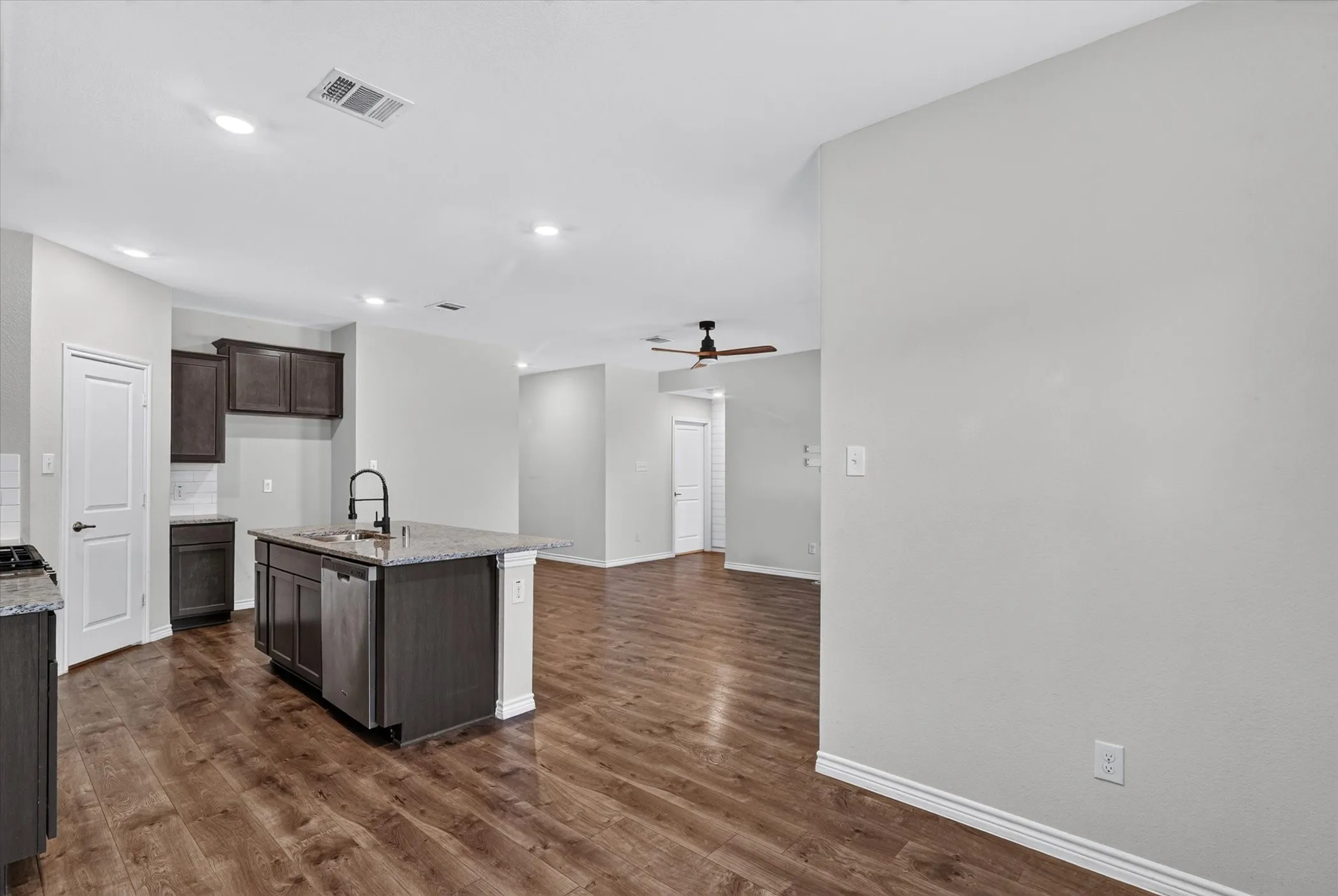 Kitchen island with a granite-style countertop, stainless steel sink, and matte black faucet