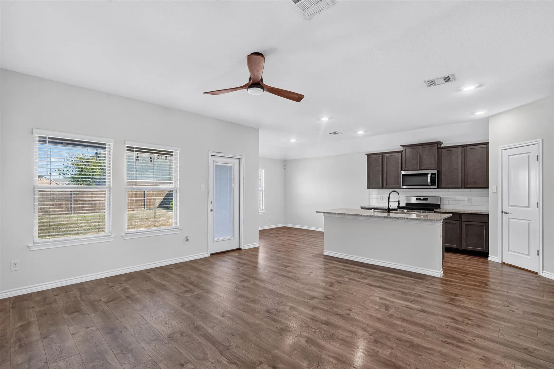 Wood-finish flooring throughout, bright white walls, and a contemporary ceiling fan