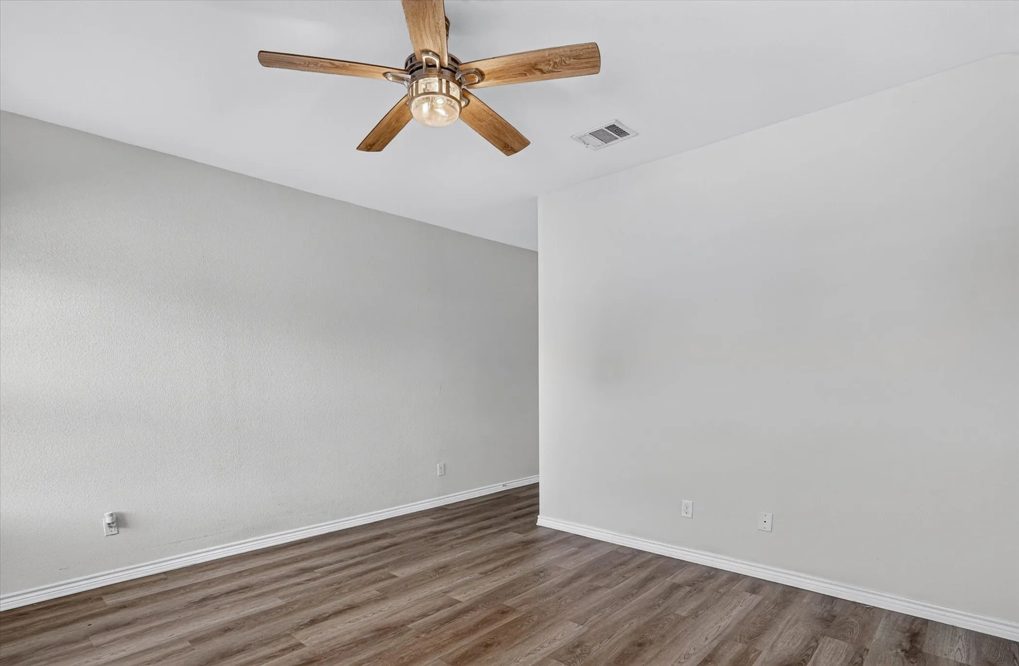 Wood-finish flooring, neutral wall tones, and a ceiling fan with integrated lighting