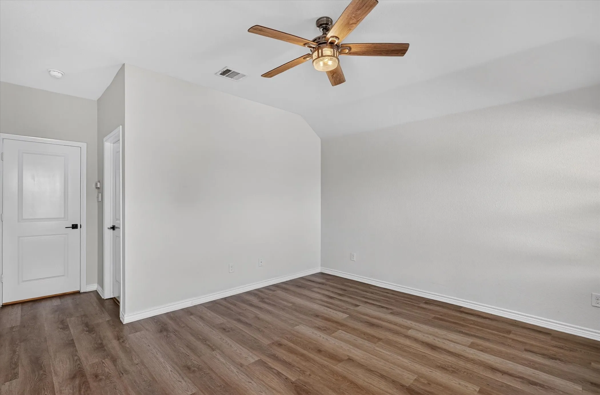 Wood-finish flooring, vaulted ceiling, and an attached ceiling fan with integrated lighting