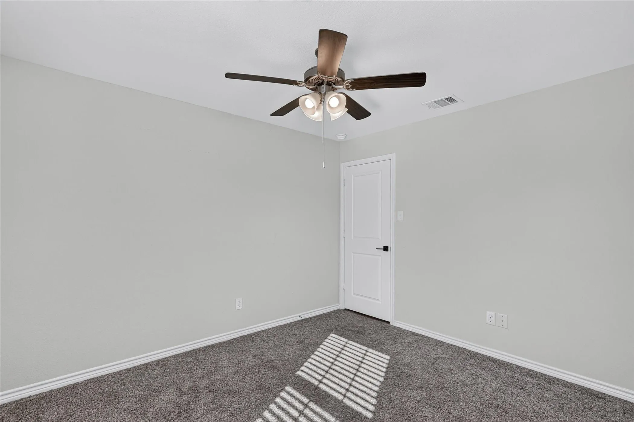 Neutral wall paint, gray carpet flooring, white trim, and a ceiling fan with integrated lighting