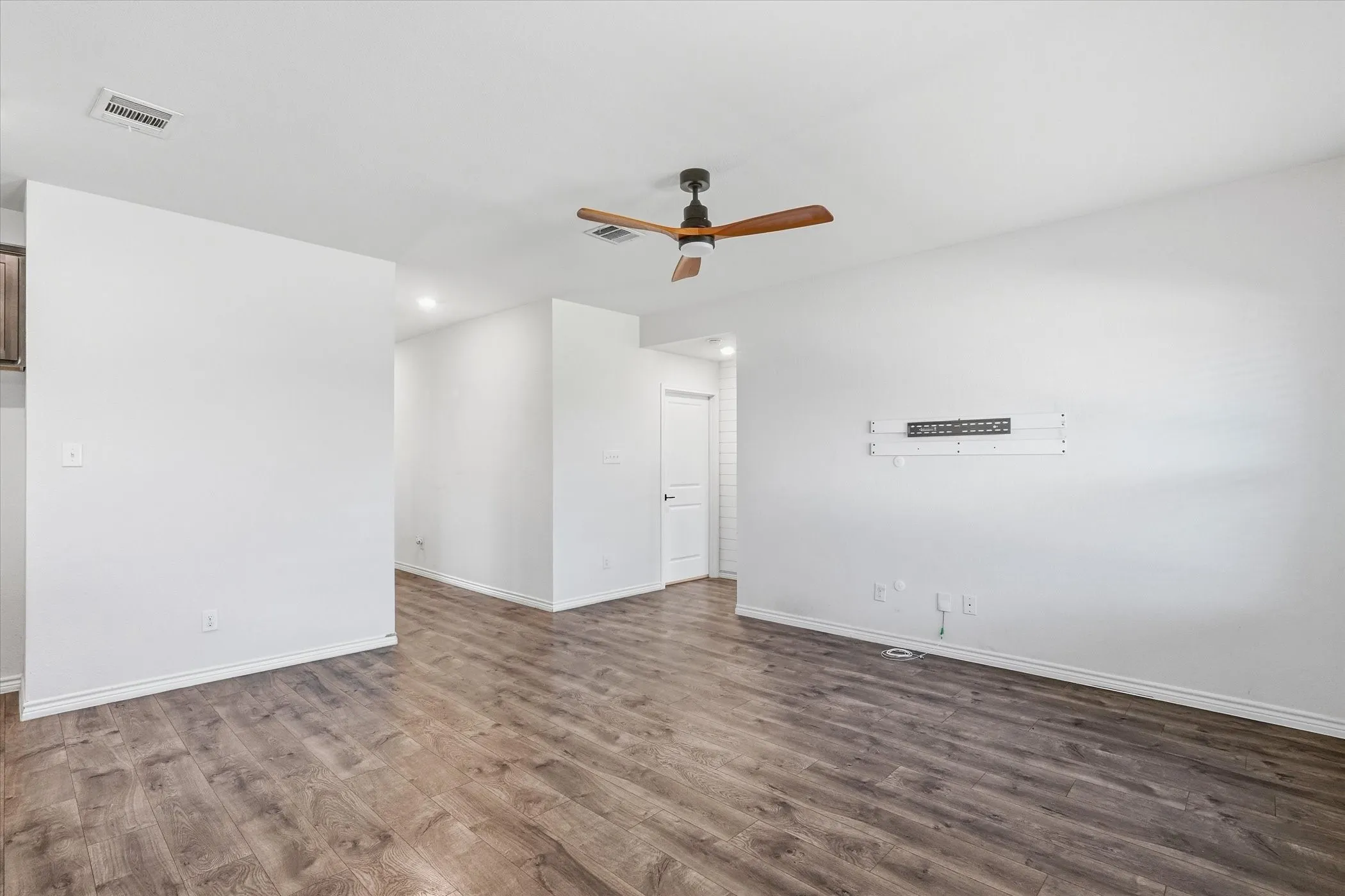 Wood-finish flooring, recessed lighting, and a ceiling fan with wood-tone blades