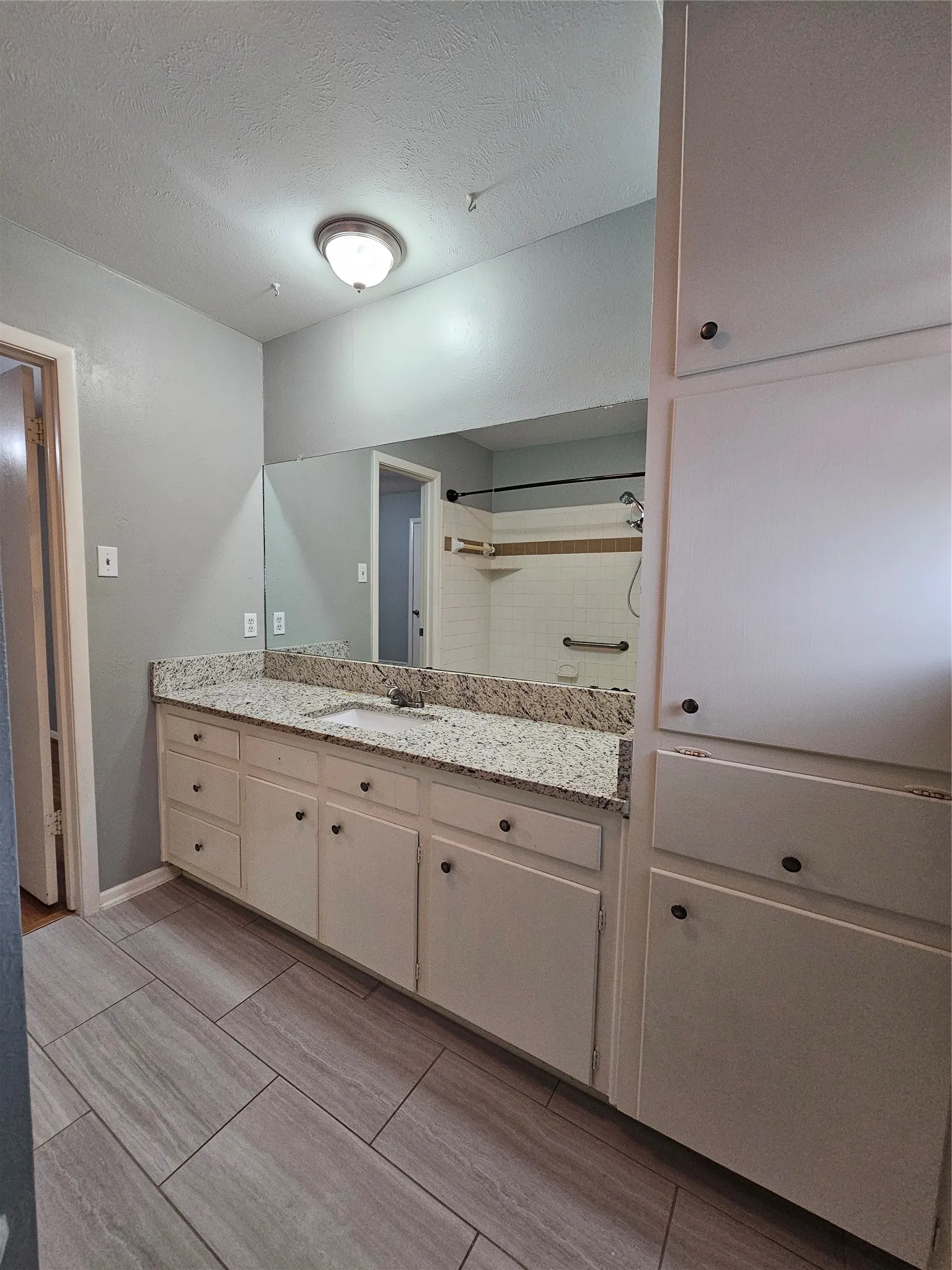 Spacious vanity with stone countertop, integrated sink, and white cabinetry