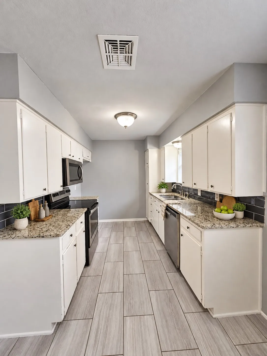 Galley kitchen featuring white cabinetry, granite-finish countertops, black subway tile backsplash, and light wood-look tile flooring