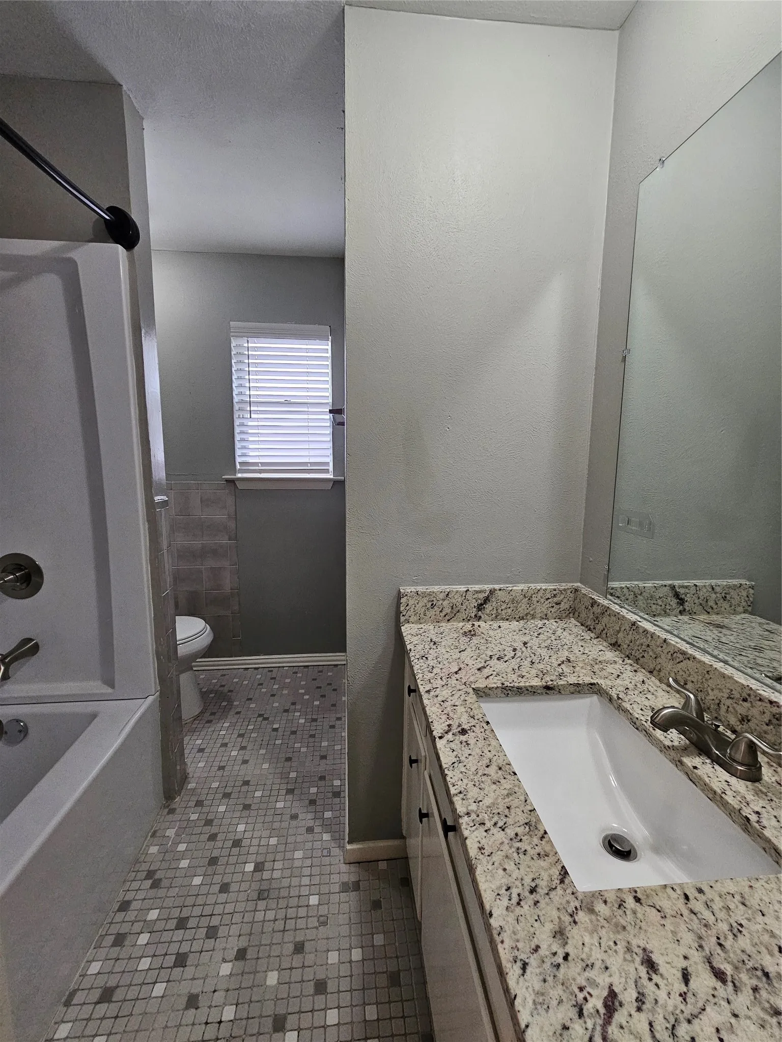 White vanity with dark hardware, a rectangular undermount sink, and a speckled​​‌​​​​‌​​‌‌​‌‌​​​‌‌​‌​‌​‌​​​‌​​ countertop