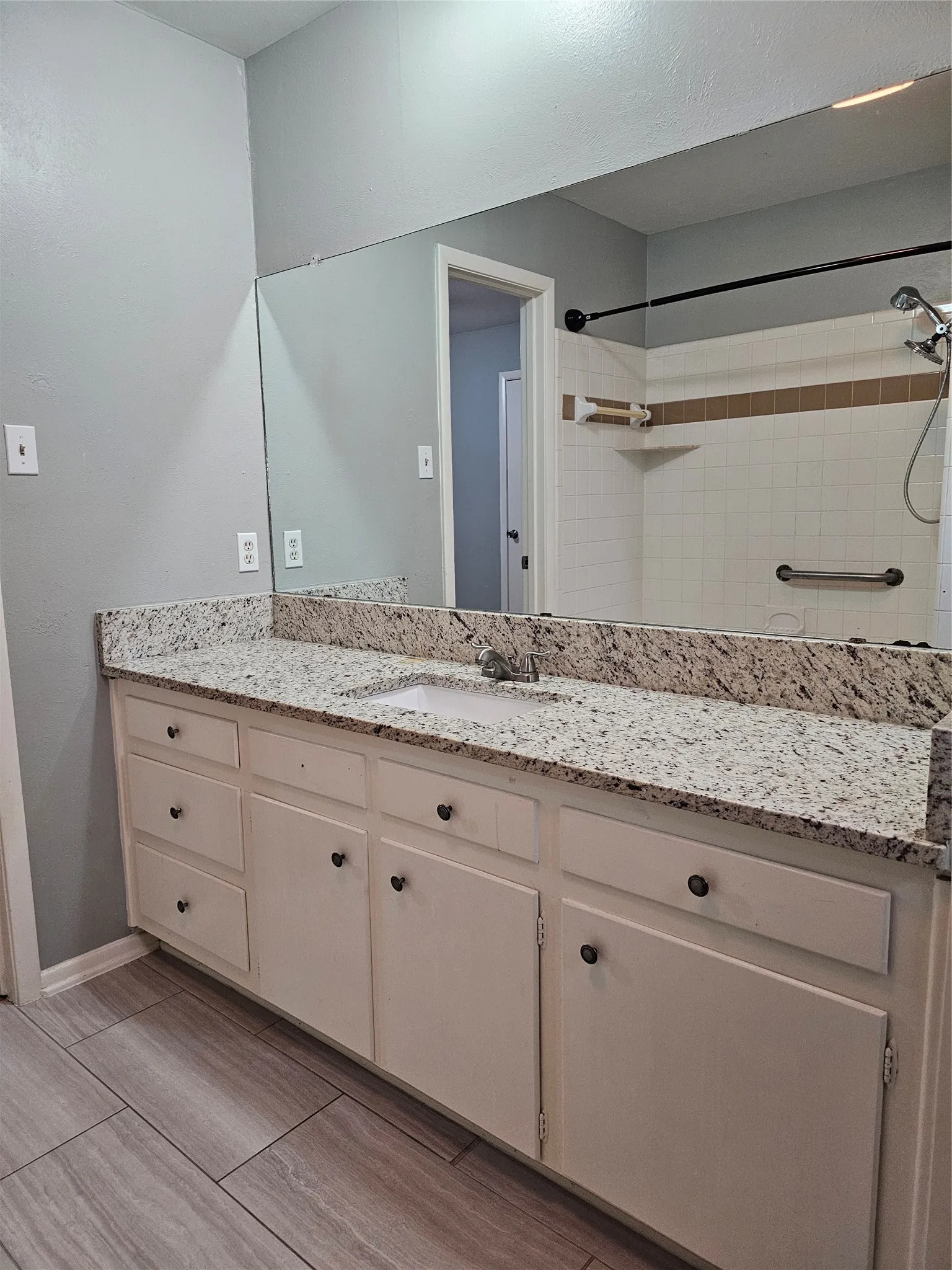 Vanity with a granite-style countertop, integrated sink, and white cabinetry