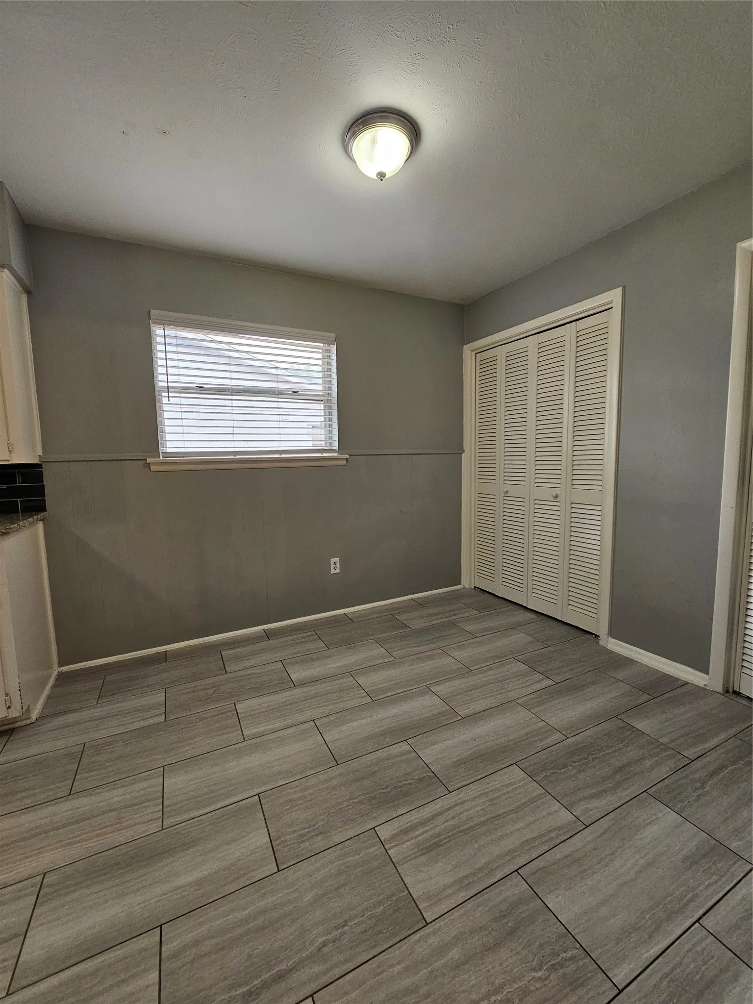 Wood-look tile flooring, louvered bi-fold closet doors, and recessed window with blinds