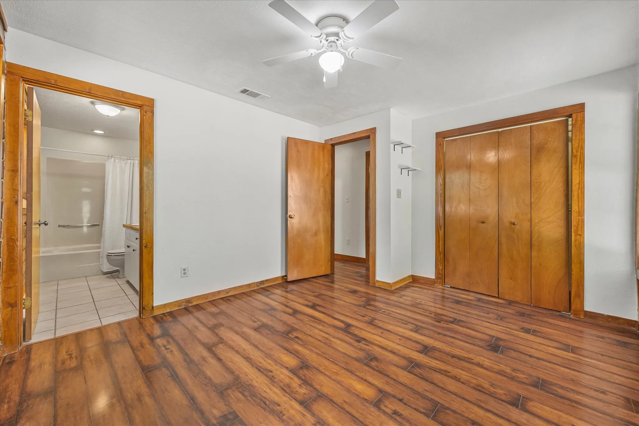Bedroom 2 with ensuite bath, tile floors, and ceiling fan.