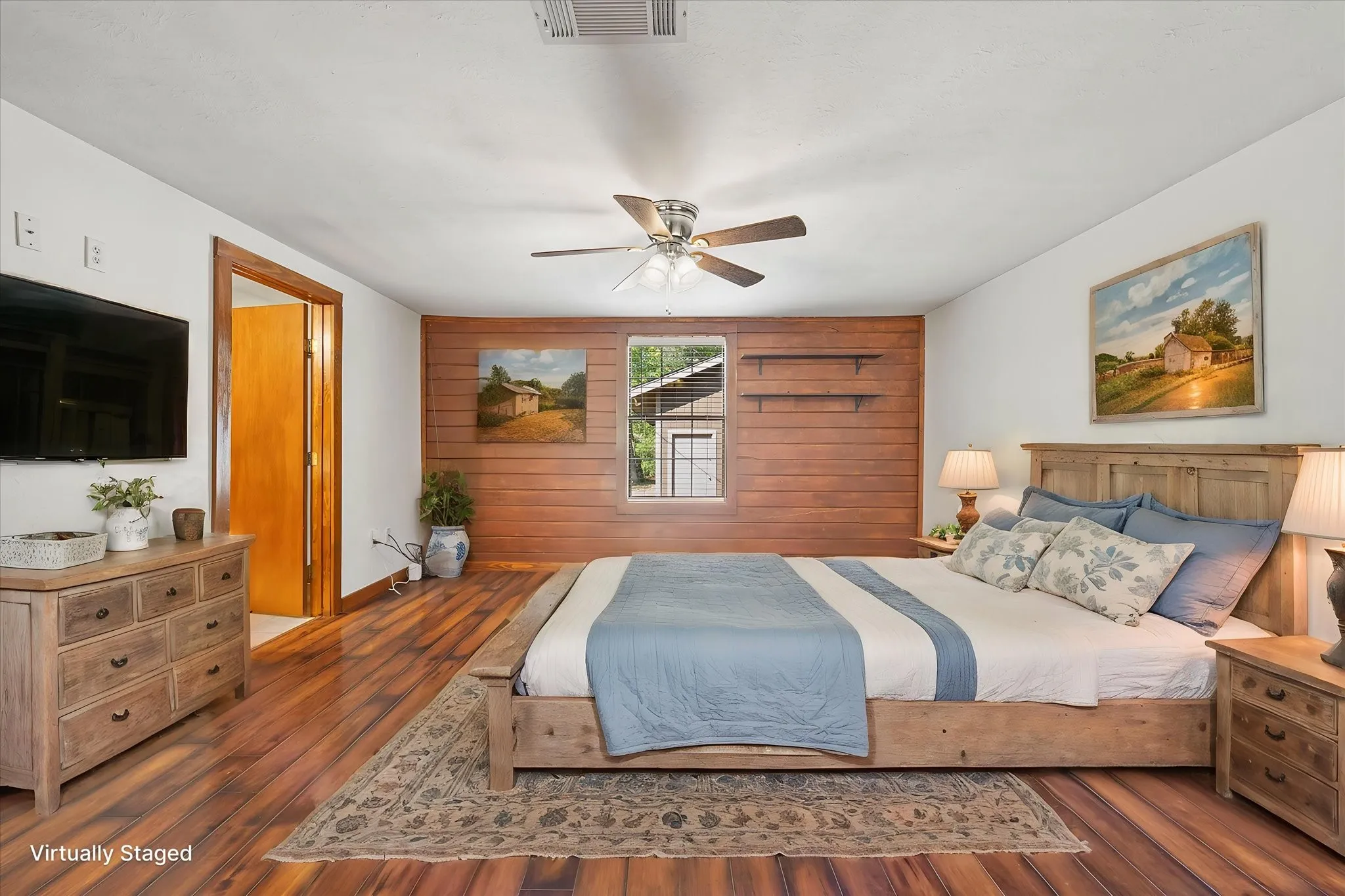 VIRTUALLY STAGED. Primary bedroom with ensuite bath and closet, plank floors, ceiling fan, fresh paint and accent wall.