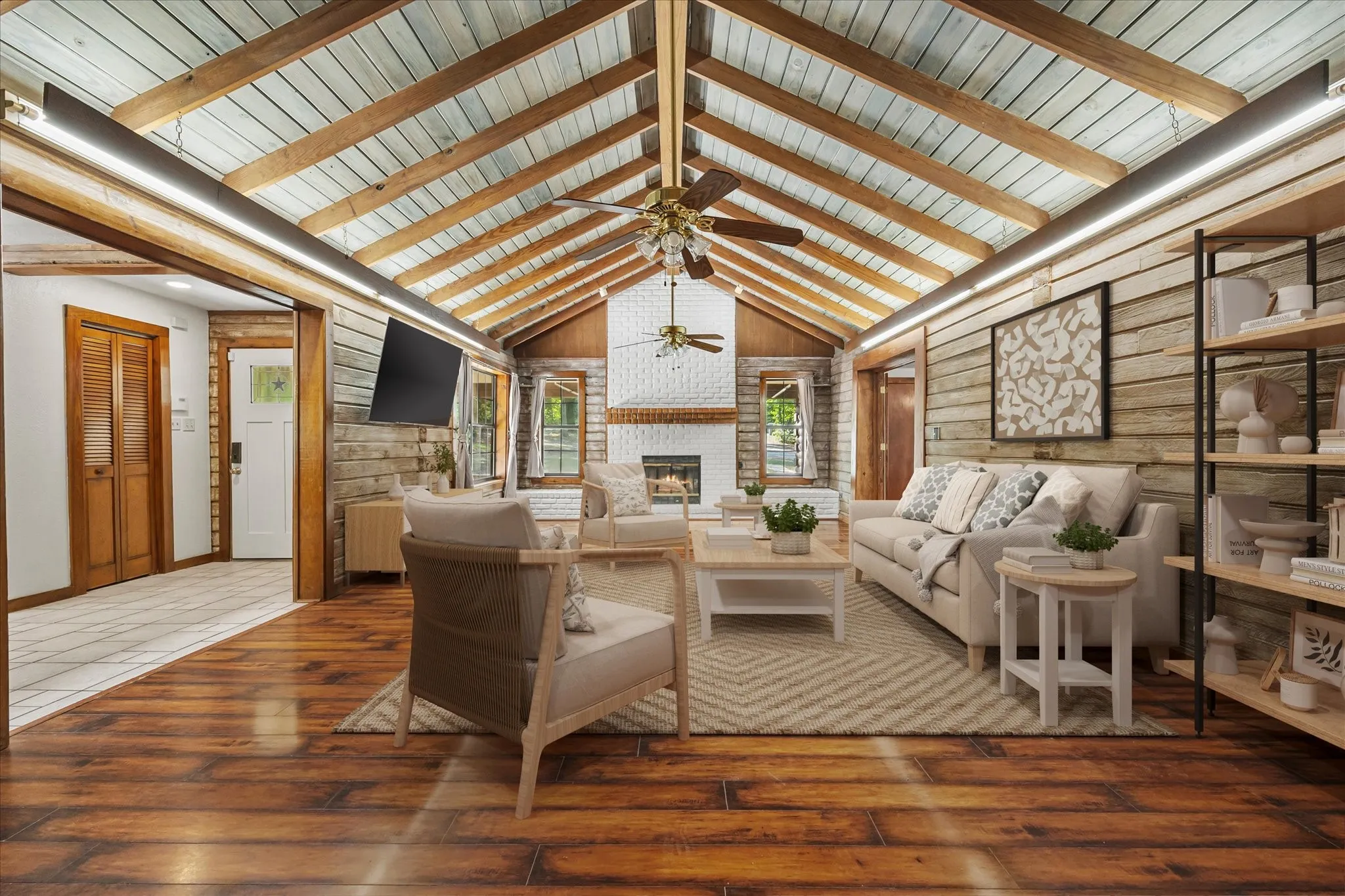 VIRTUALLY STAGED. The living room features a wood-beamed vaulted ceiling, plank flooring, ceiling fans and beautiful woodburning fireplace.