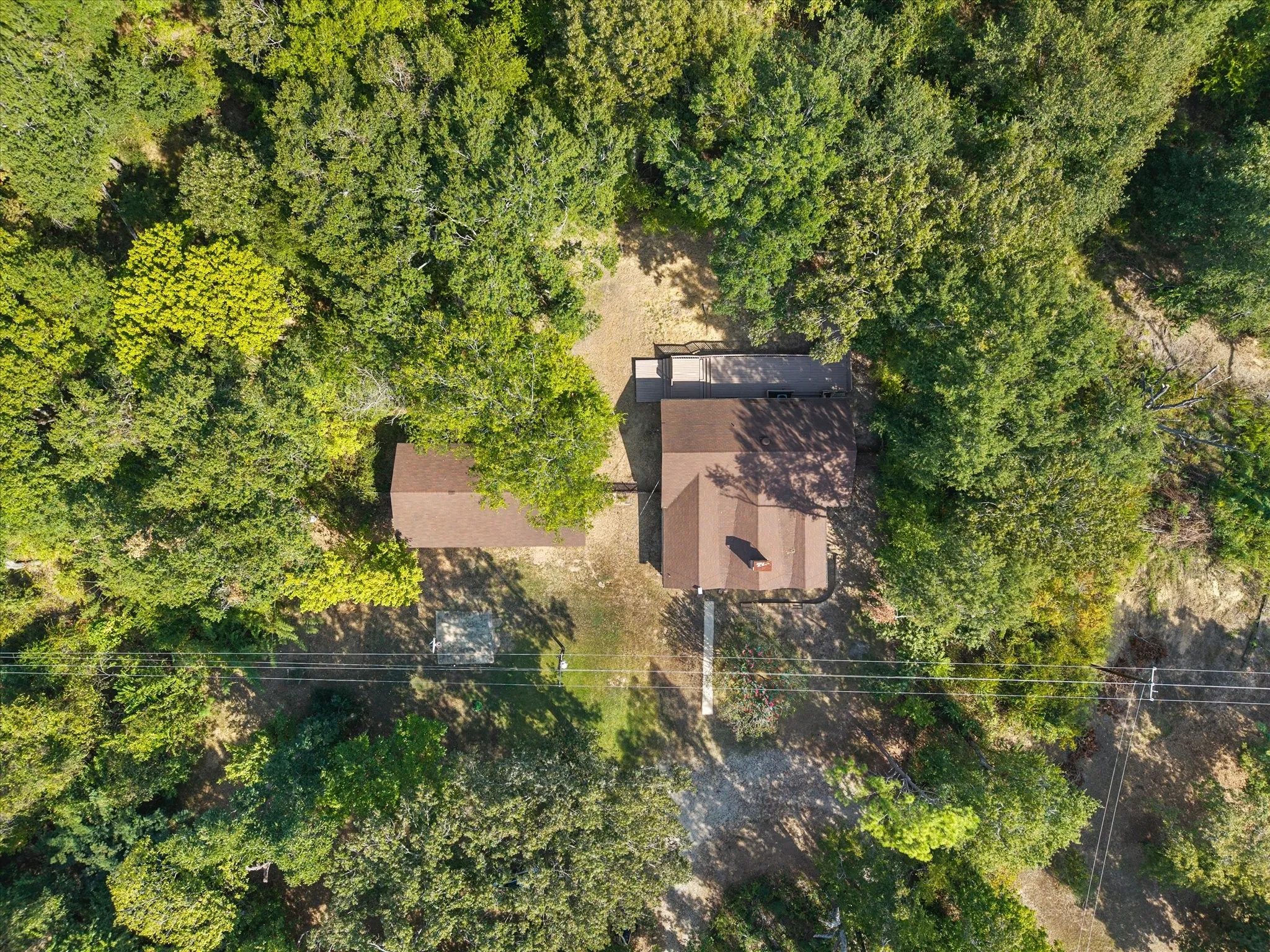 Overhead of the log home with stone fireplace and wood deck and the four car garage/workshop, nestled one one acre of mature trees.
