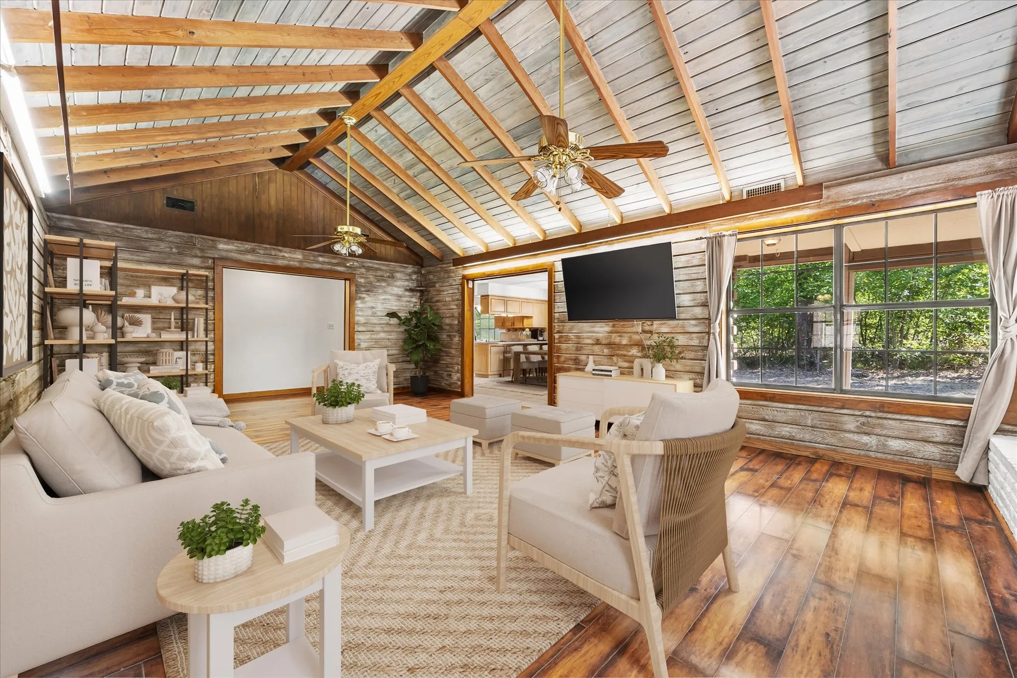 VIRTUALLY STAGED living room with vaulted and beamed ceilings, plank floors, ceiling fans, fireplace and ample windows to bring the outdoors in.