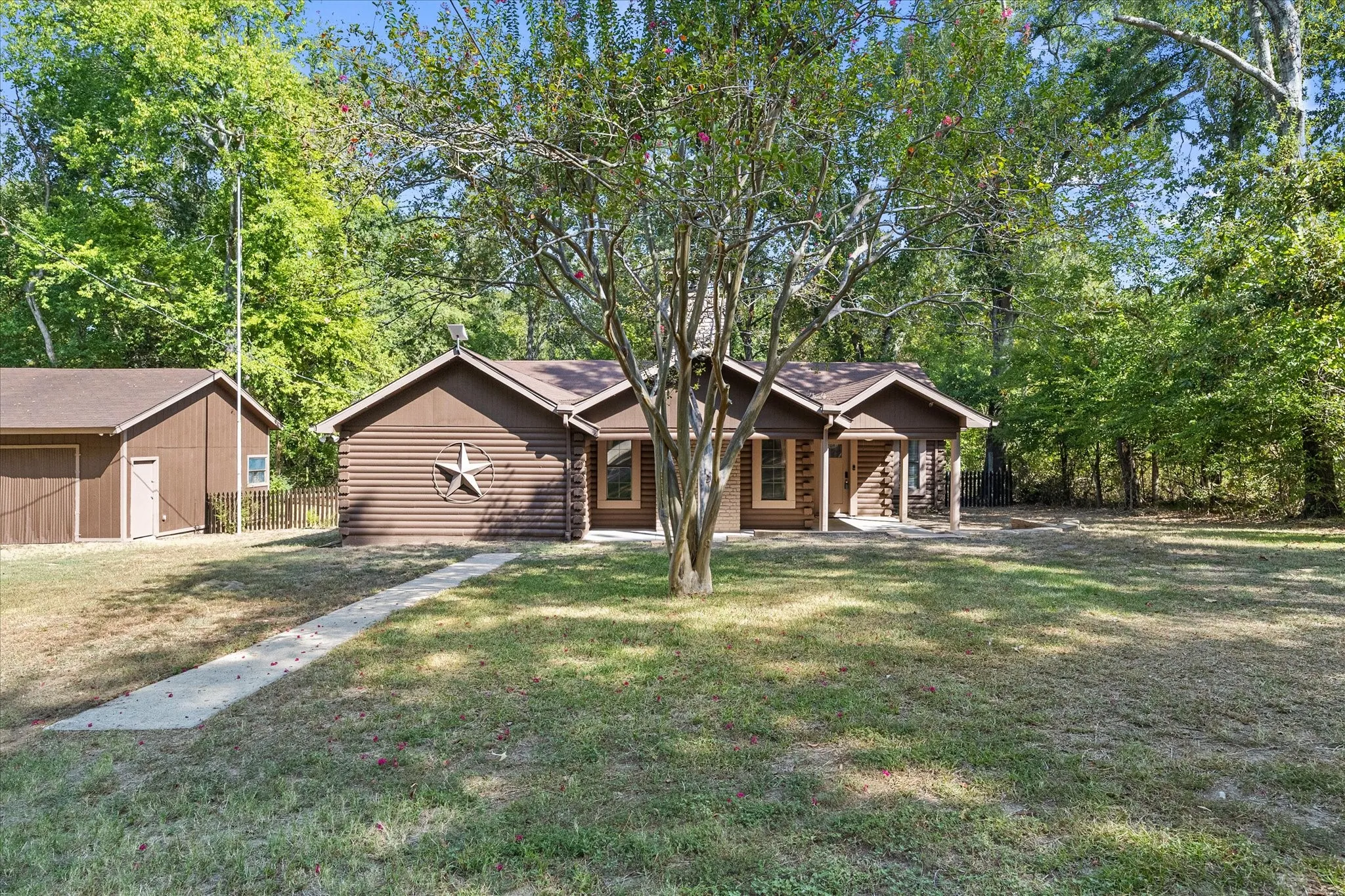 Close up of 3/3 log home with detached four car garage/workshop. Big covered front porch. Surrounded by trees for your privacy.