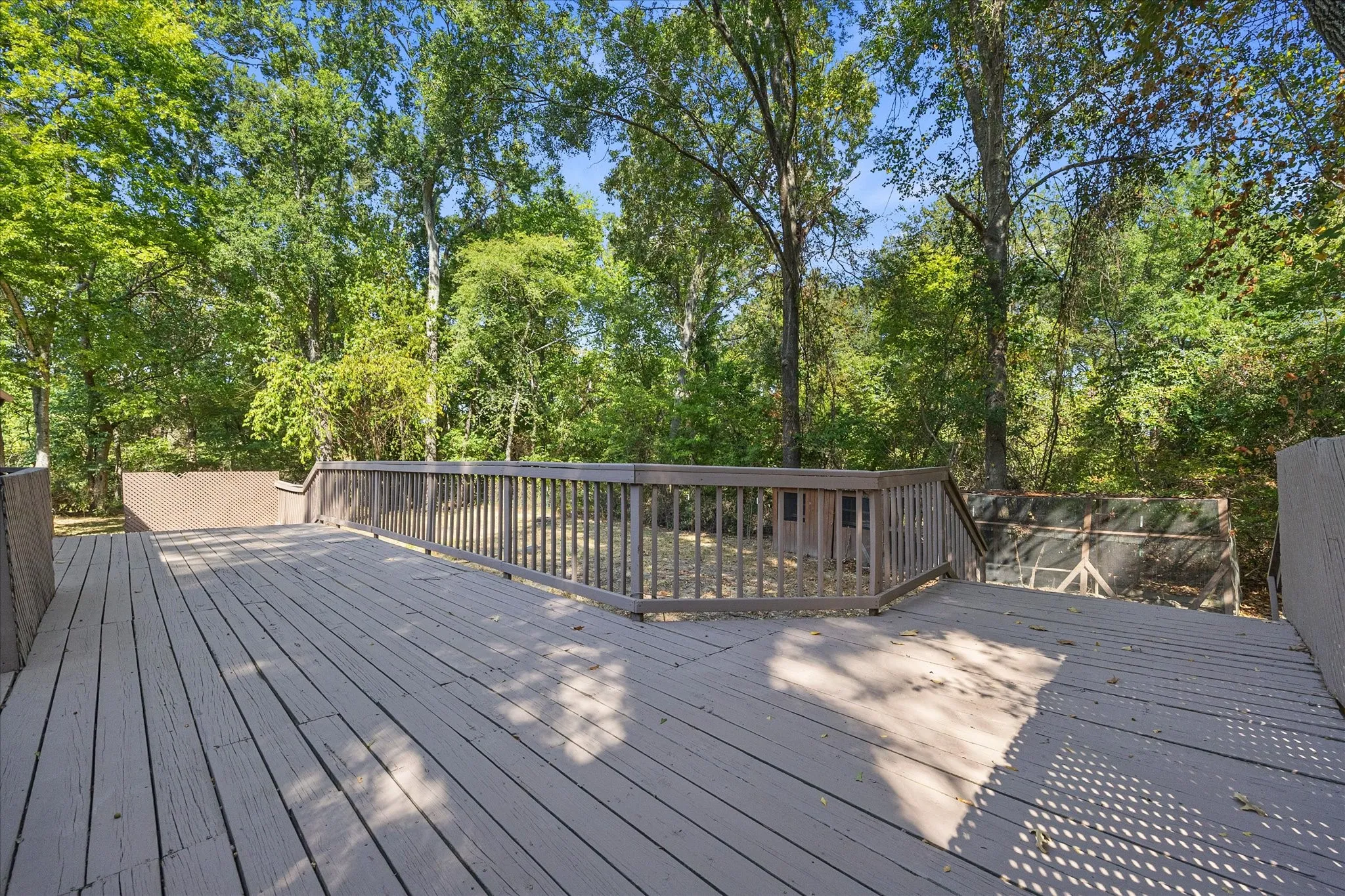 Refreshed wood deck extends the length of the house and features a railing and multiple levels.