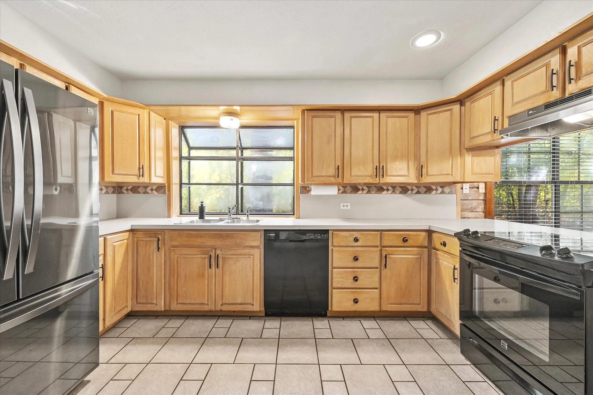 The kitchen opens to the back yard and the dining area and features ample light, tile flooring, fresh paint and quality appliances. Refrigerator stays.