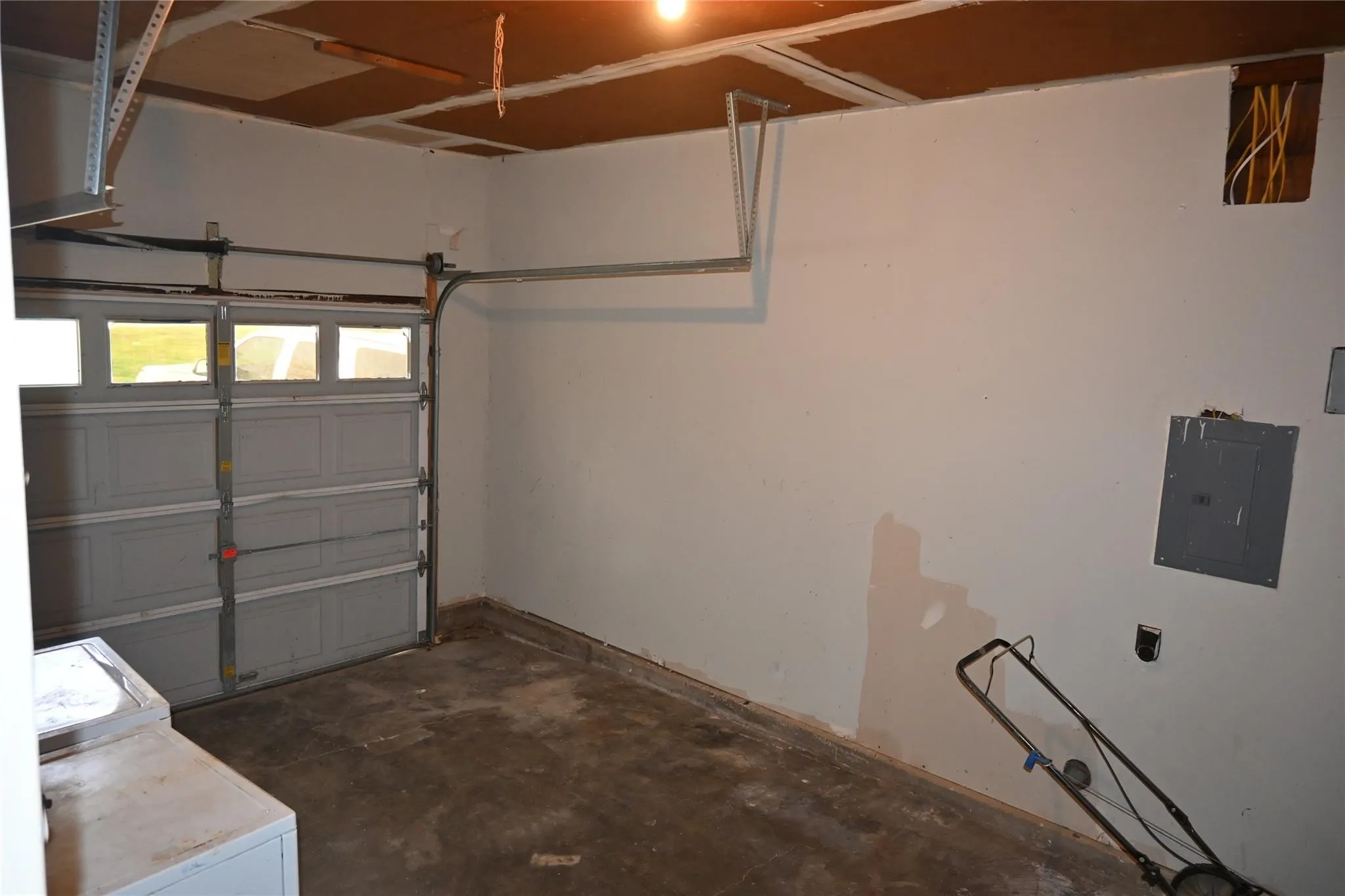 Garage space featuring a built-in overhead light fixture, a paneled garage door with windows, and a wall-mounted electrical panel