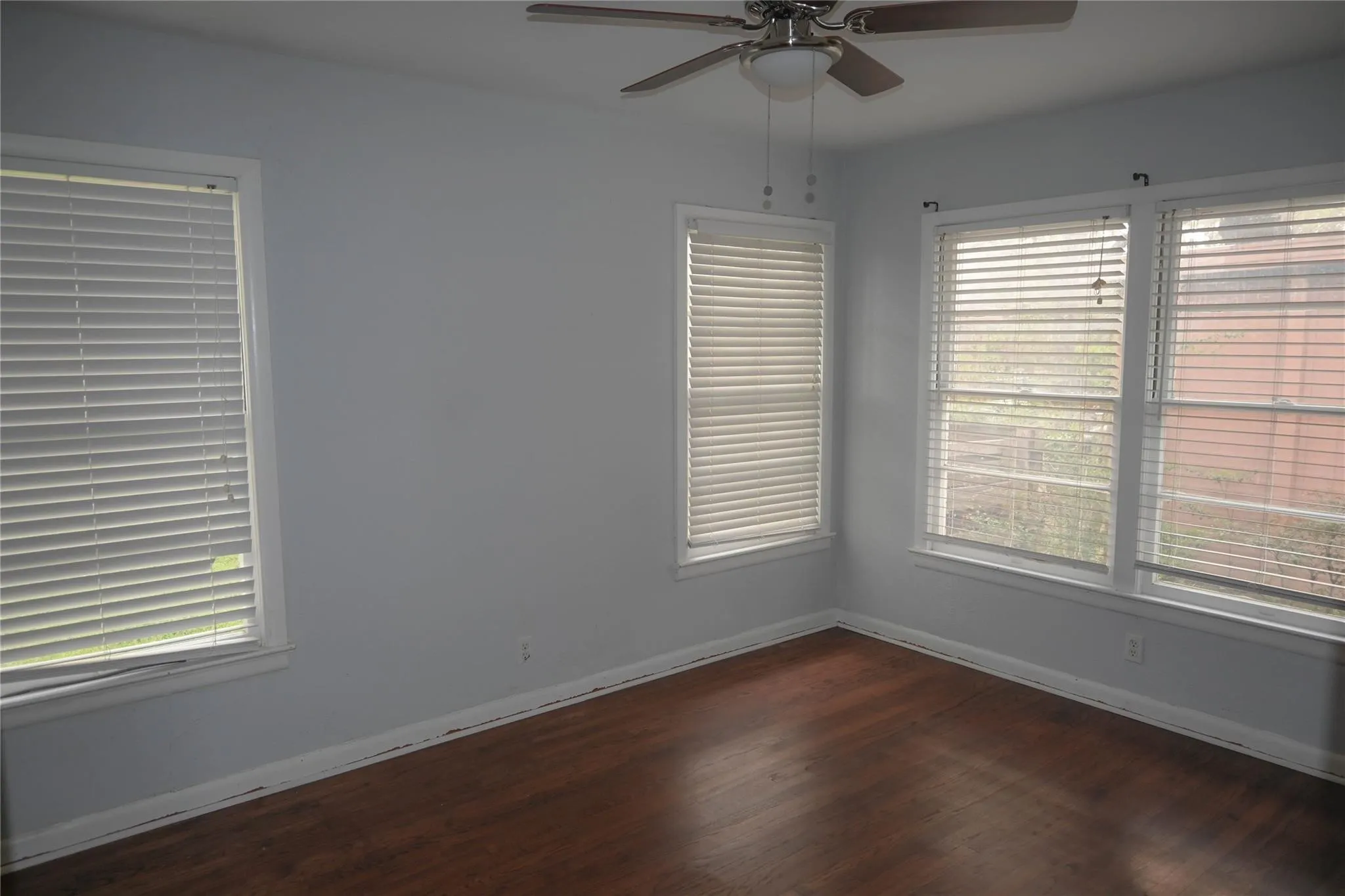 Wood-finish flooring with multiple windows featuring blinds