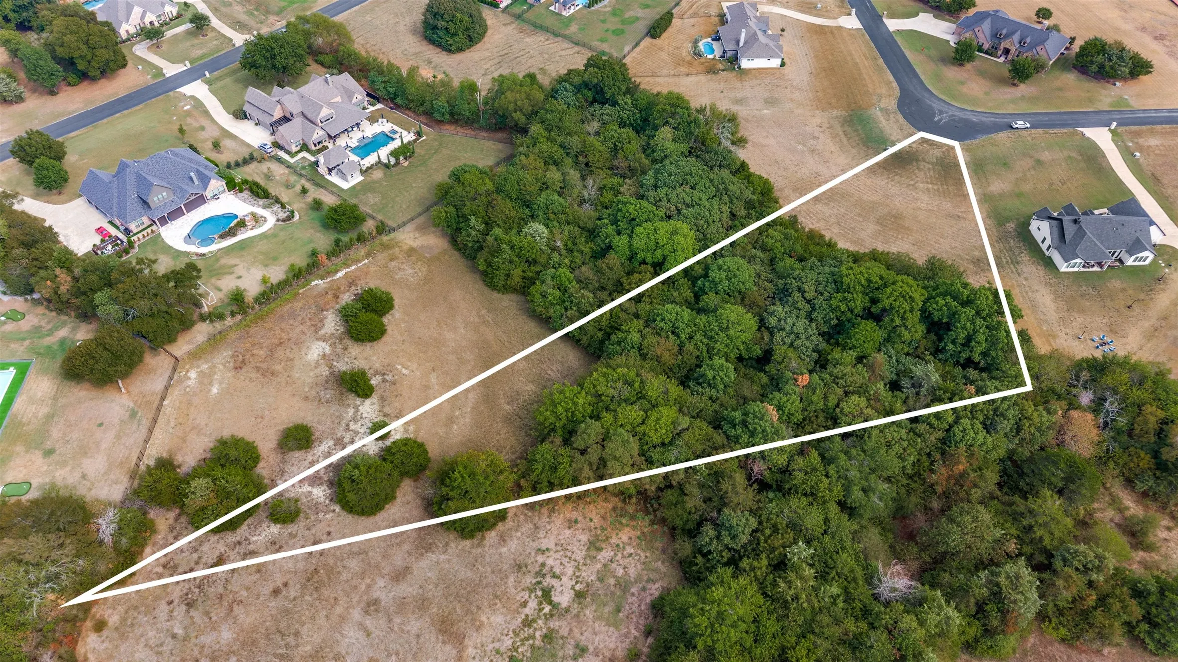 Aerial with a different drone elevation and angle showing more open space in the back of the lot, and the beautiful native trees!