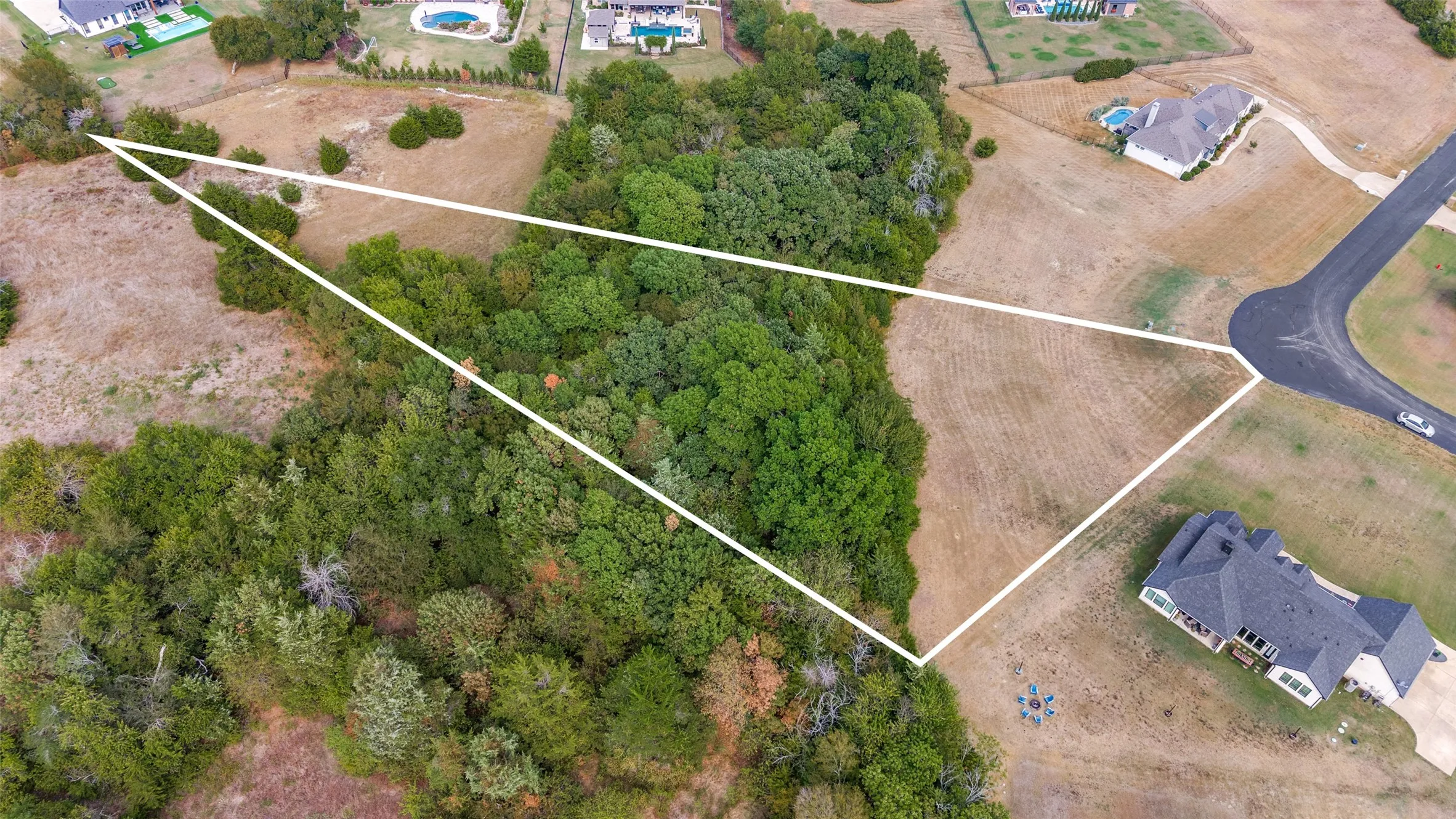 Aerial shows the 2.02 acres with large front grassy area, open area in back, wooded area in middle. Also shows large circle in street where Twilight Dr. bends.