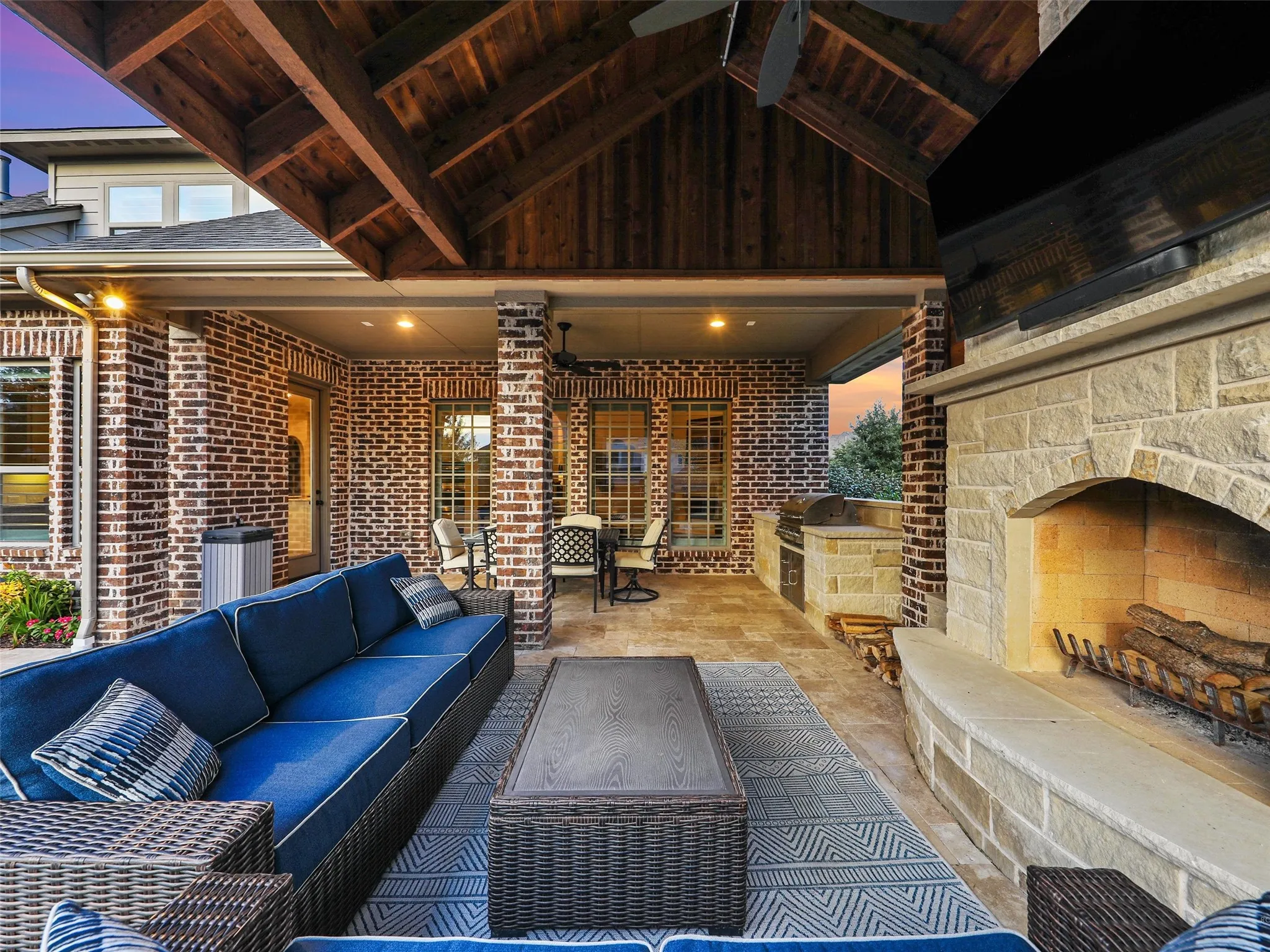 The covered outdoor living center extends the home's entertaining space into the backyard. The roof extension is finished internally with stained cedar, bringing warmth and architectural character overhead. A built-in grilling area and custom fireplace are constructed from 100% Leuders limestone, while the fireplace itself features full masonry construction. Together, these elements create a substantial outdoor gathering space for grilling, dining, relaxing by the fire, or entertaining alongside the pool and spa.