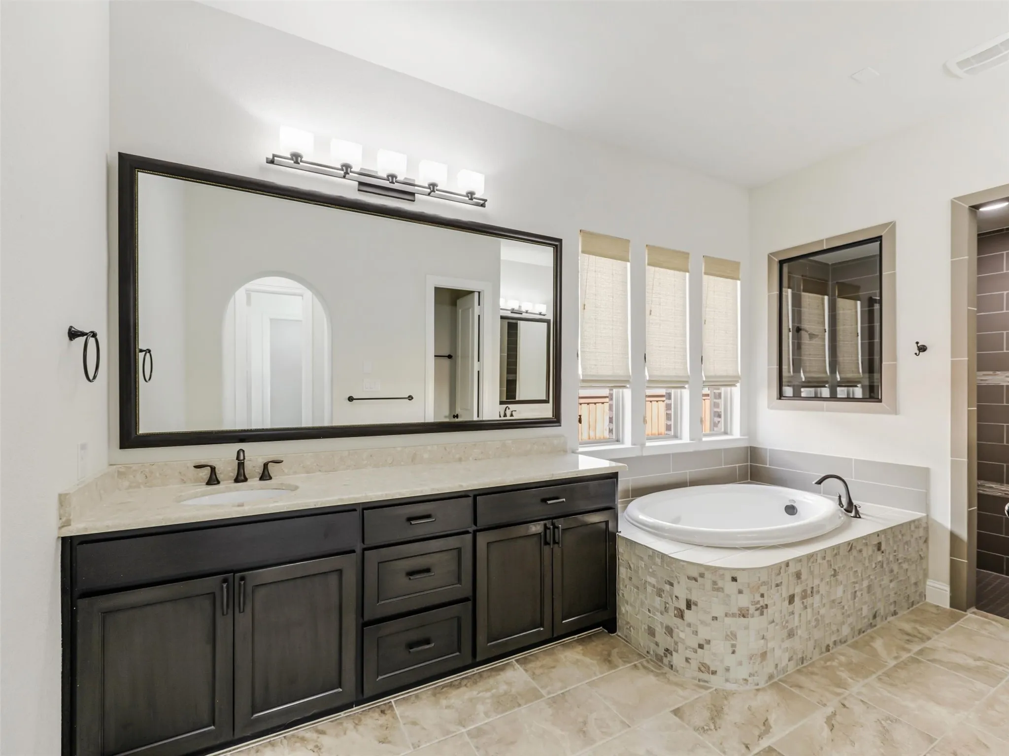 The primary suite offers a spacious private retreat with an approximately 8-by-9-foot sitting area that can be used for reading, relaxing, or creating a quiet morning lounge. The generously sized ensuite bath measures approximately 11 by 18 feet and features a separate shower, soaking tub, and separate vanities with individual sinks. An approximately 10-by-14-foot walk-in closet provides extensive wardrobe storage and offers the added convenience of direct access to the laundry room, creating an efficient and thoughtfully planned connection between the spaces.