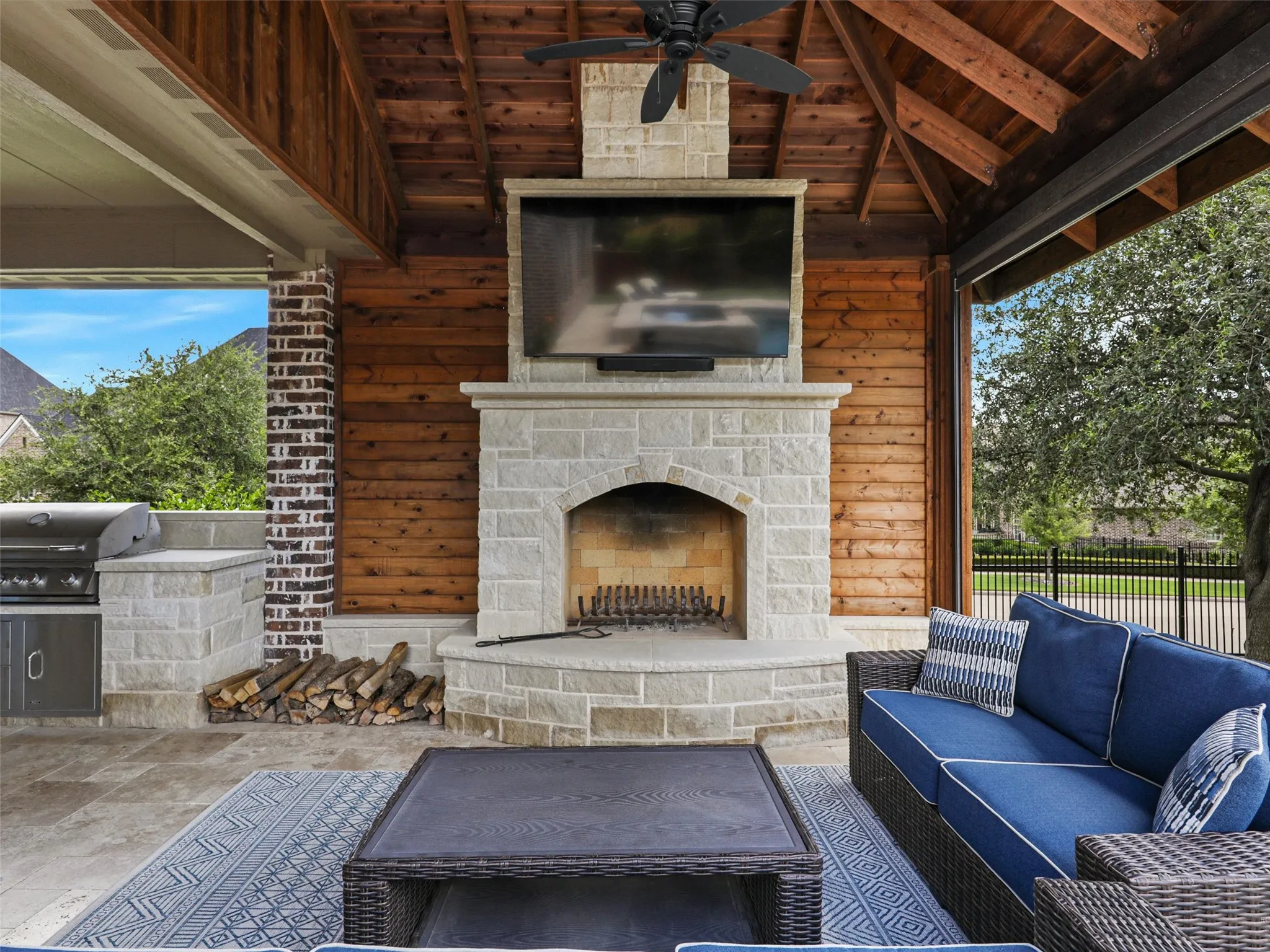 The covered outdoor living center extends the home's entertaining space into the backyard. The roof extension is finished internally with stained cedar, bringing warmth and architectural character overhead. A built-in grilling area and custom fireplace are constructed from 100% Leuders limestone, while the fireplace itself features full masonry construction. Together, these elements create a substantial outdoor gathering space for grilling, dining, relaxing by the fire, or entertaining alongside the pool and spa.
