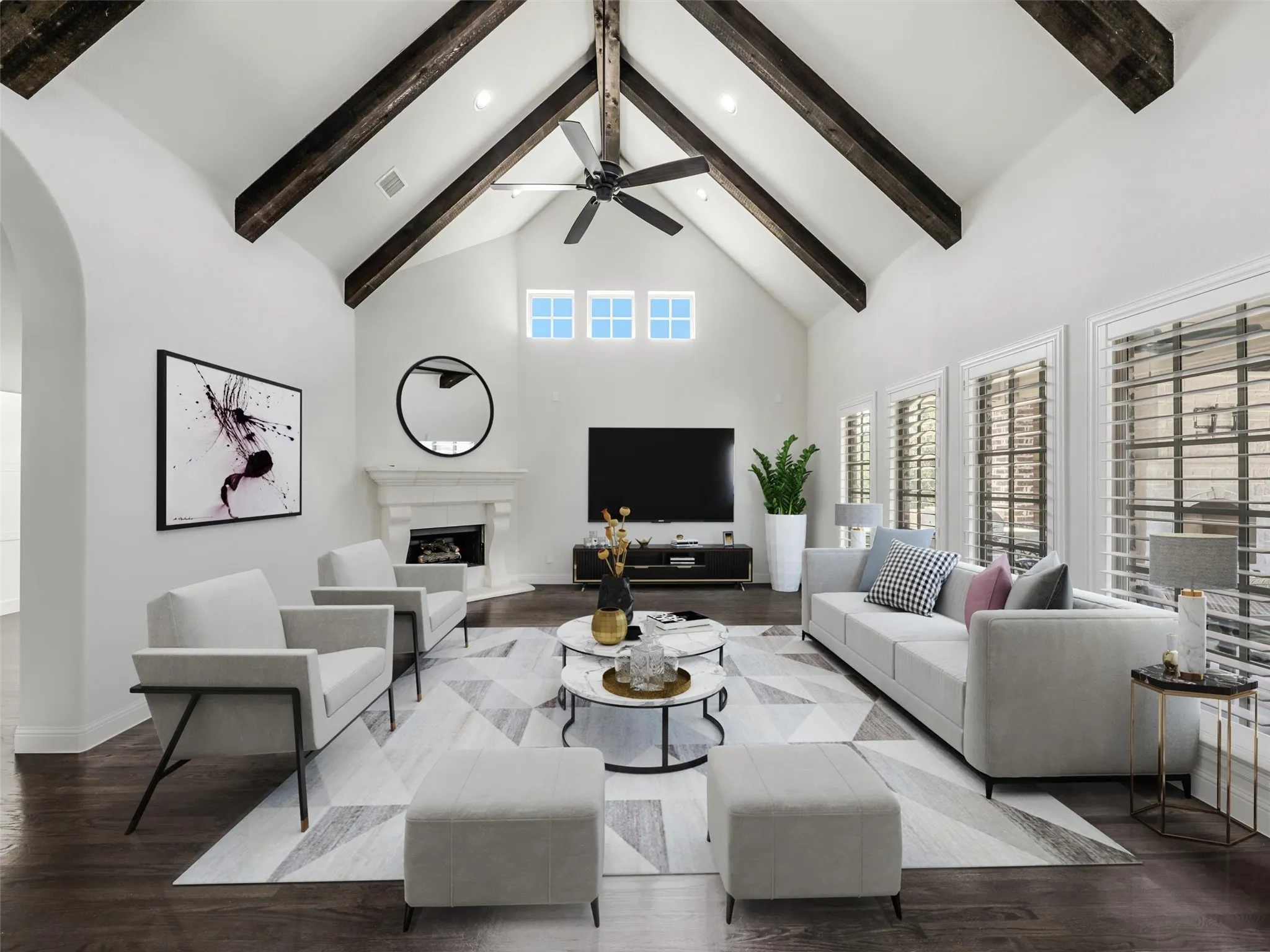 VIRTUALLY STAGED. The main living room offers an impressive sense of scale with soaring vaulted ceilings accented by exposed beams. A corner fireplace creates an inviting focal point, while plantation shutters add timeless style and privacy. Hardwood flooring extends throughout the main living spaces, creating warmth and continuity across the home's interior.