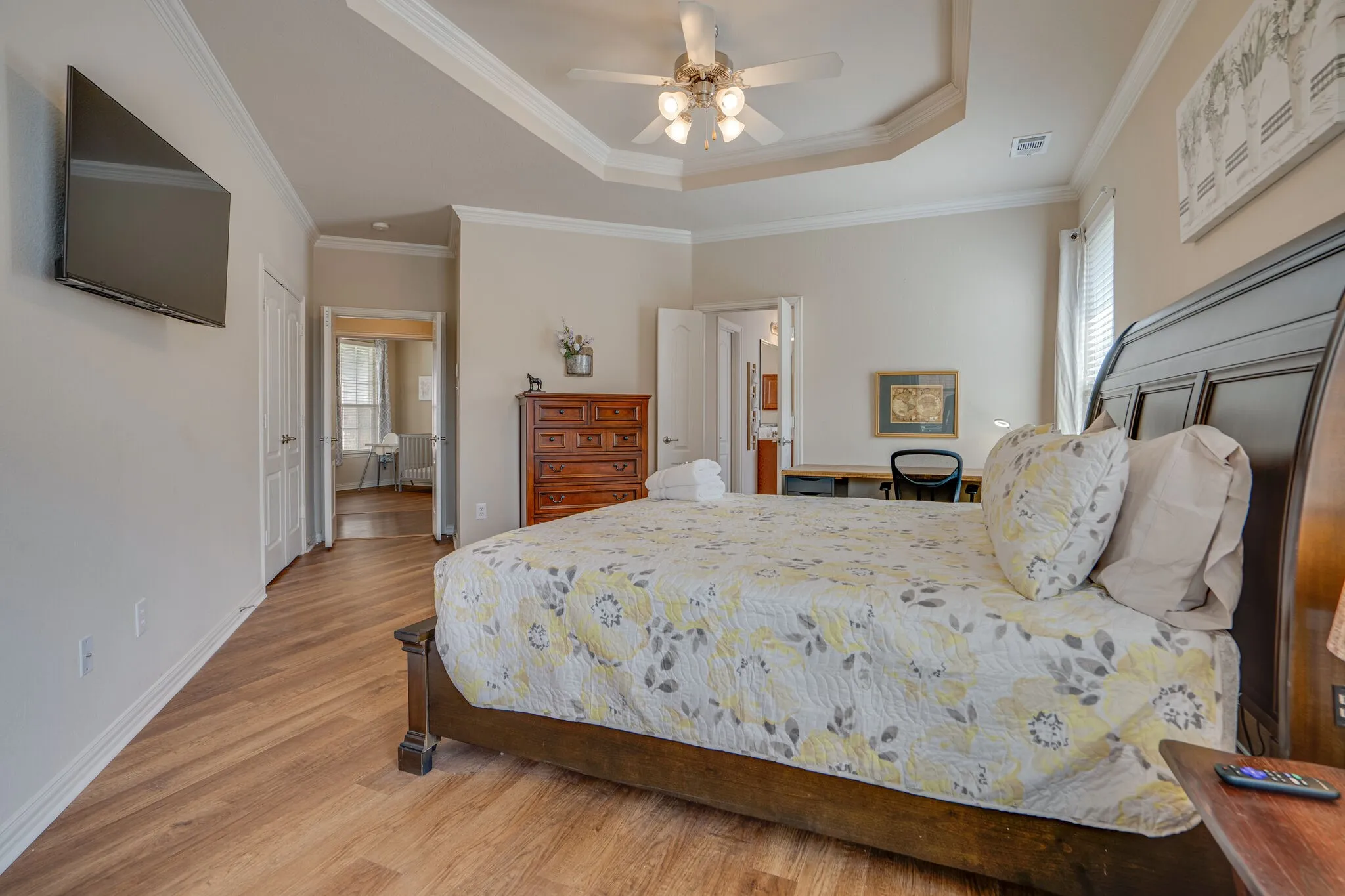 Tray ceiling with crown molding, wood-finish flooring, ceiling fan, and built-in desk
