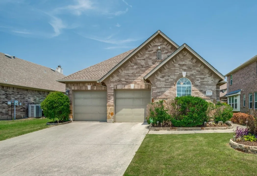 Brick facade with stone accents, arched window, and dual garage doors
