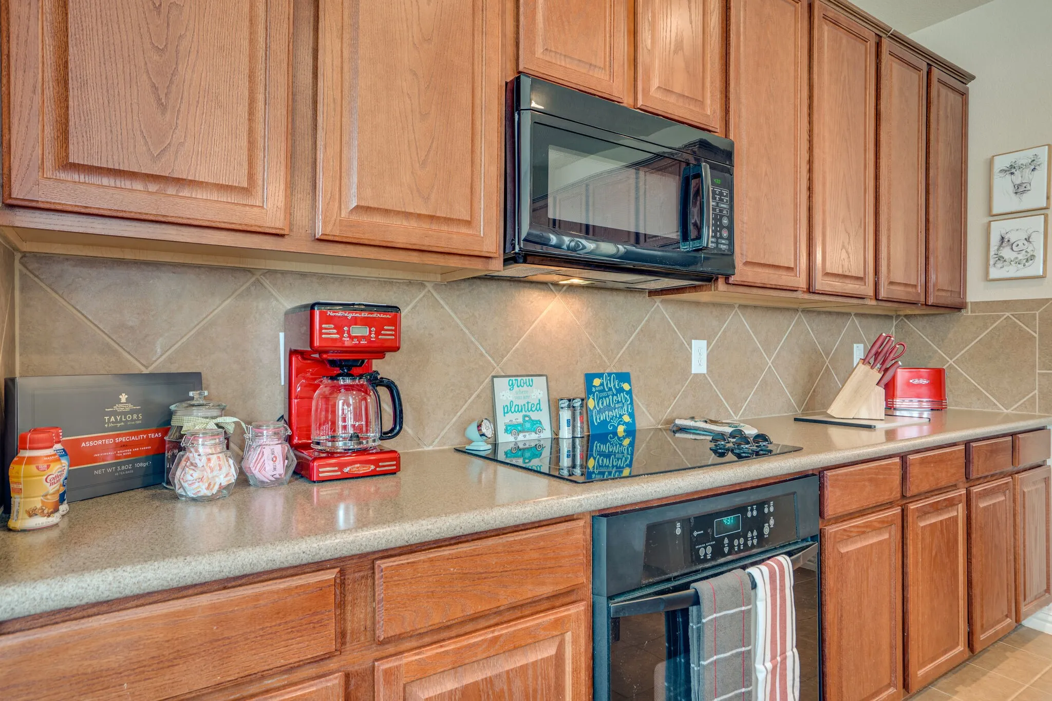 Wood-finish cabinetry with panel doors, integrated black microwave, electric cooktop, built-in oven, and light-toned countertops