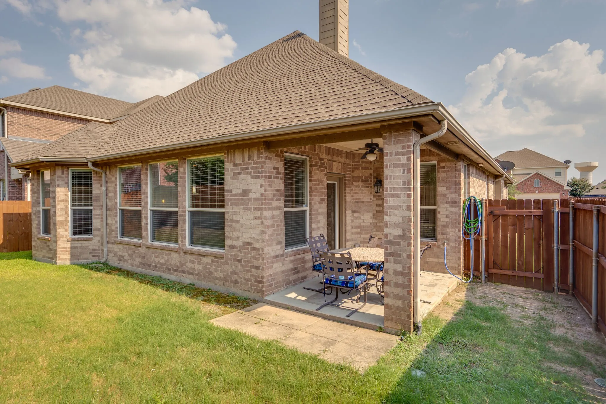 Covered patio featuring a ceiling fan, brick exterior, and a fenced yard