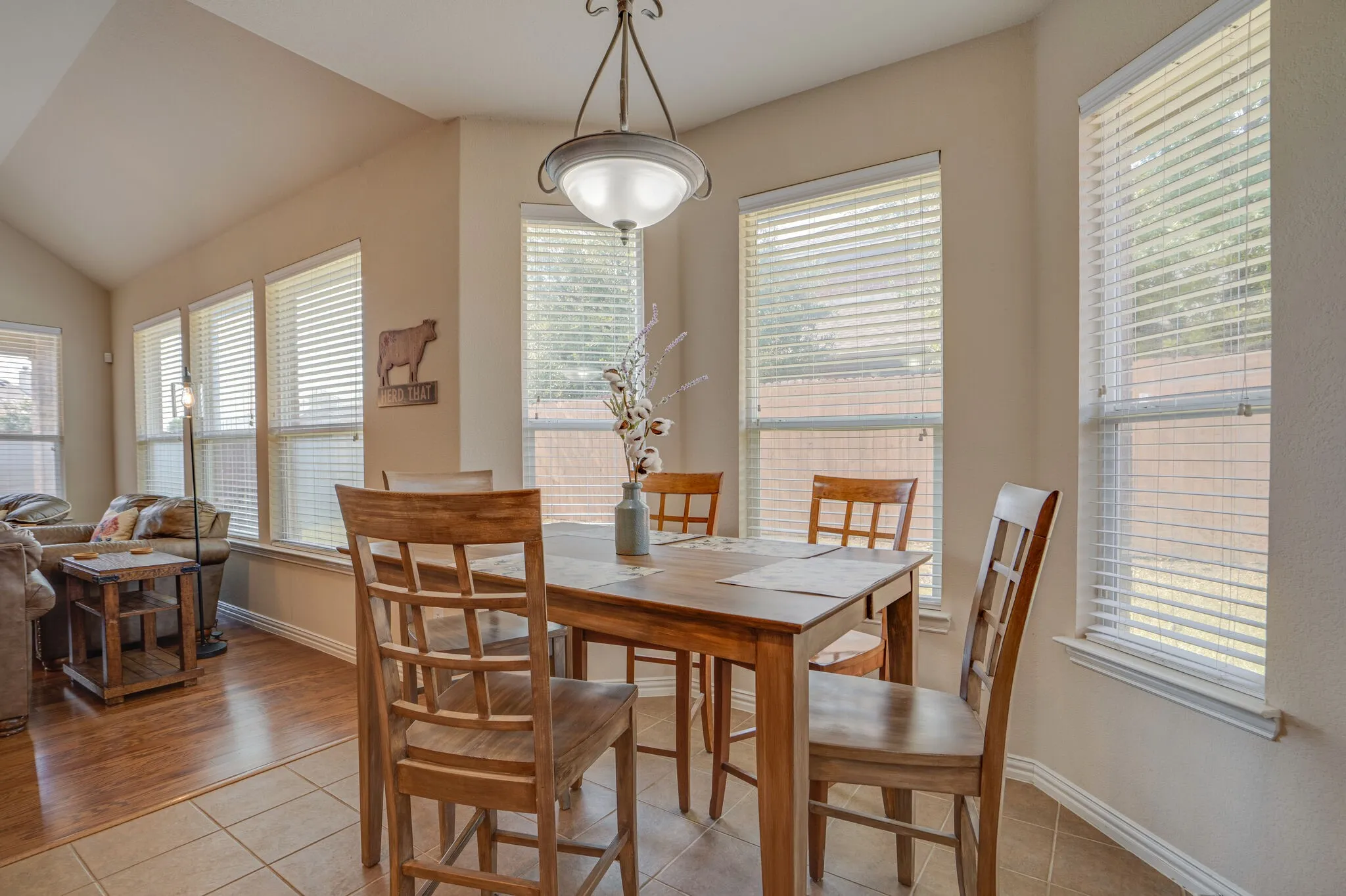 Dining area with extensive natural light from multiple windows, ceramic tile flooring, and a decorative ceiling light fixture