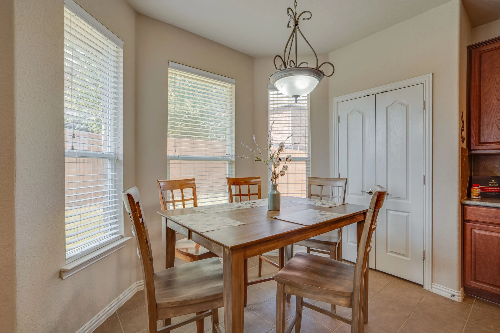 Recessed bay windows with blinds, overhead decorative light fixture, built-in cabinetry, and tile flooring