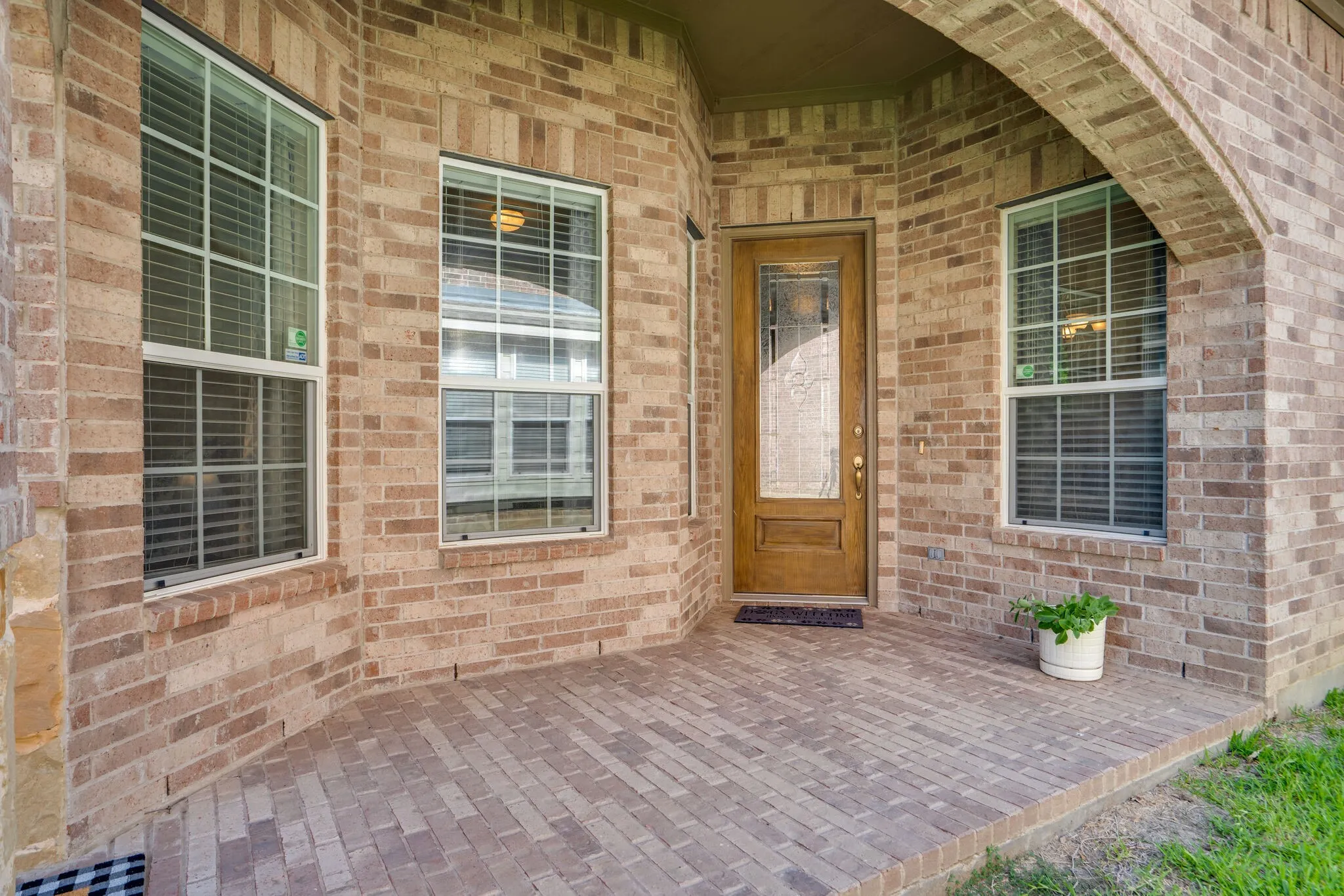 Brick facade with an arched entry and a wood-finish door featuring decorative glass